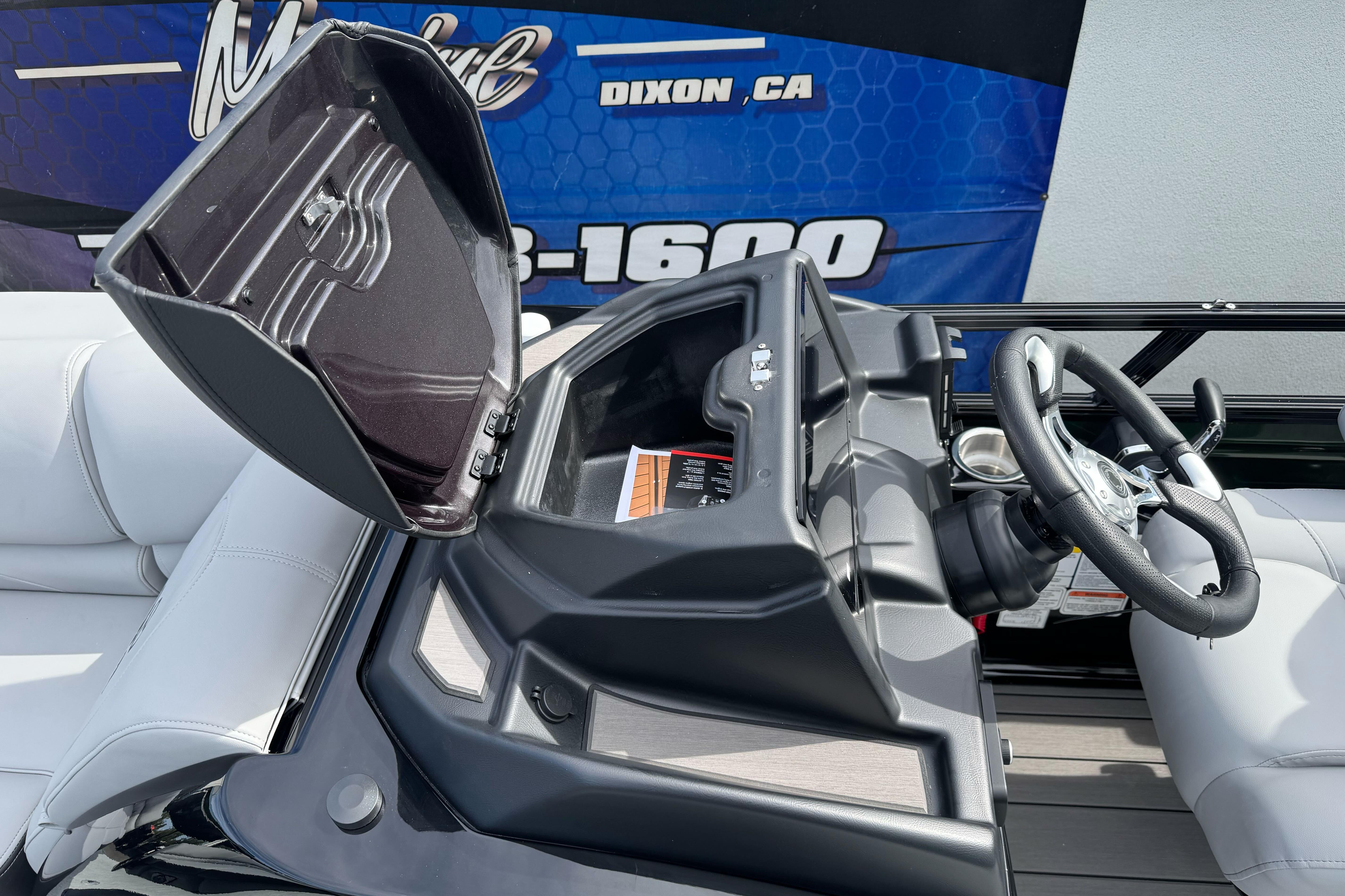 2026 Regency 250 DL boat dashboard with open storage compartment and steering wheel.