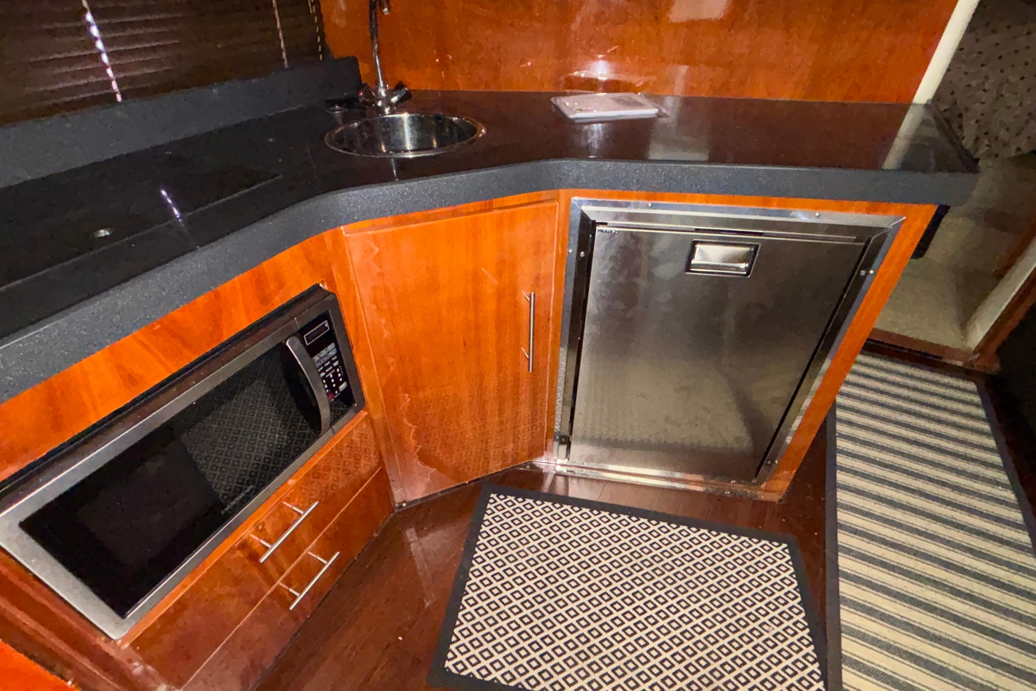 2012 Regal 42 Sport Coupe yacht kitchen with microwave, sink, and stainless steel fridge.