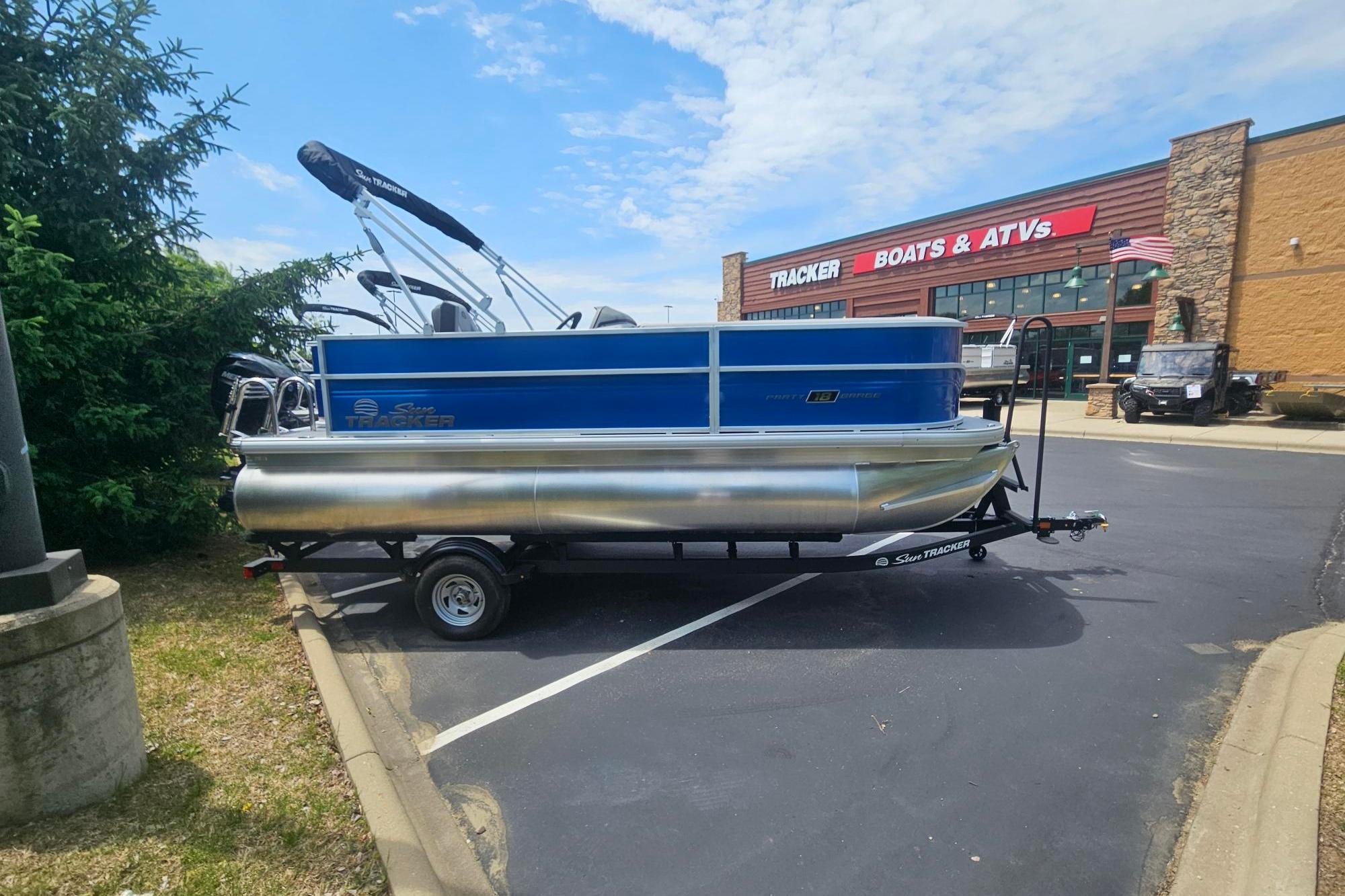 2026 Sun Tracker Party Barge 18 DLX pontoon boat parked outside dealership.