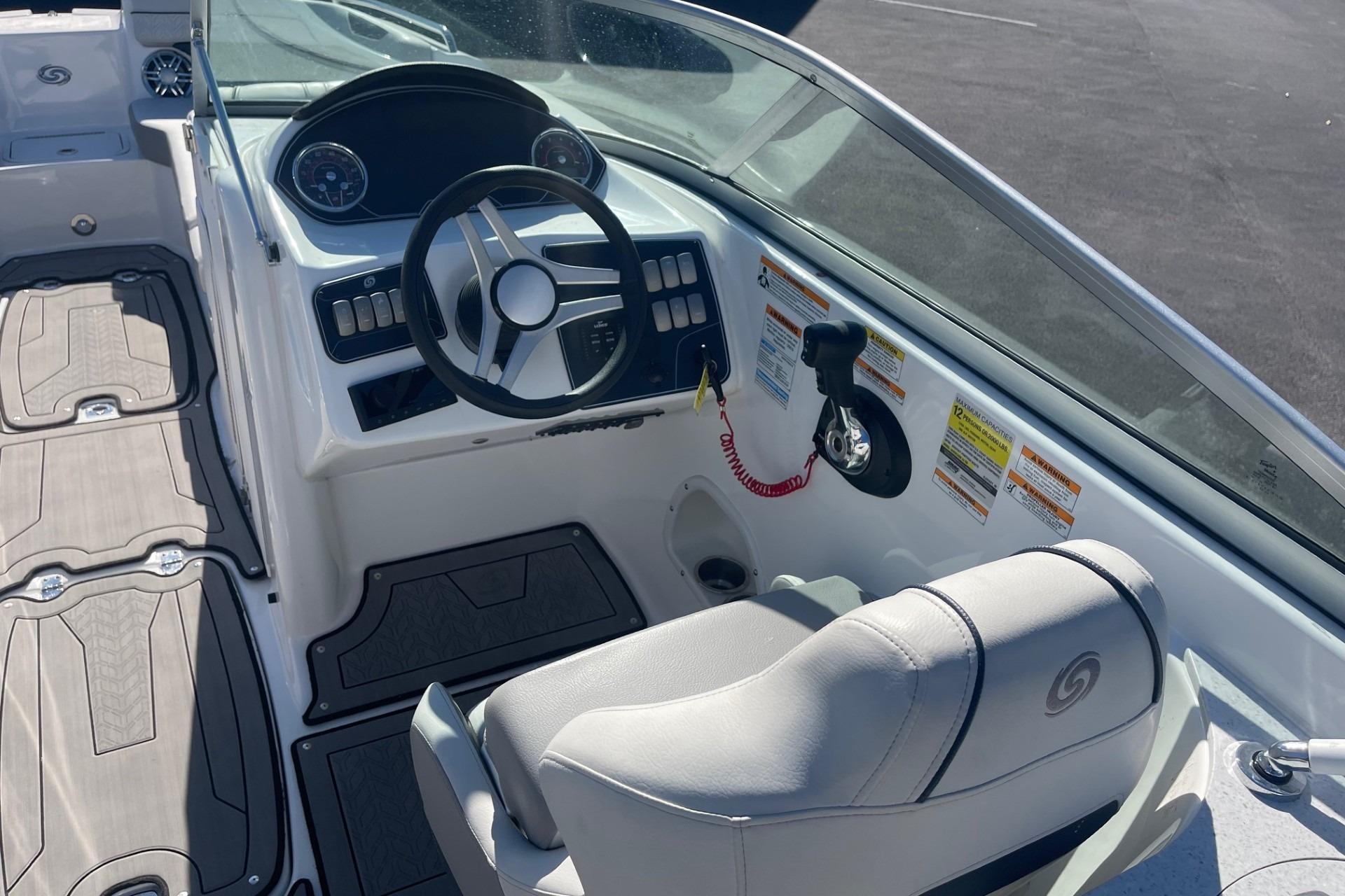 2023 Hurricane SunDeck 2400 OB boat interior with steering wheel and seating.