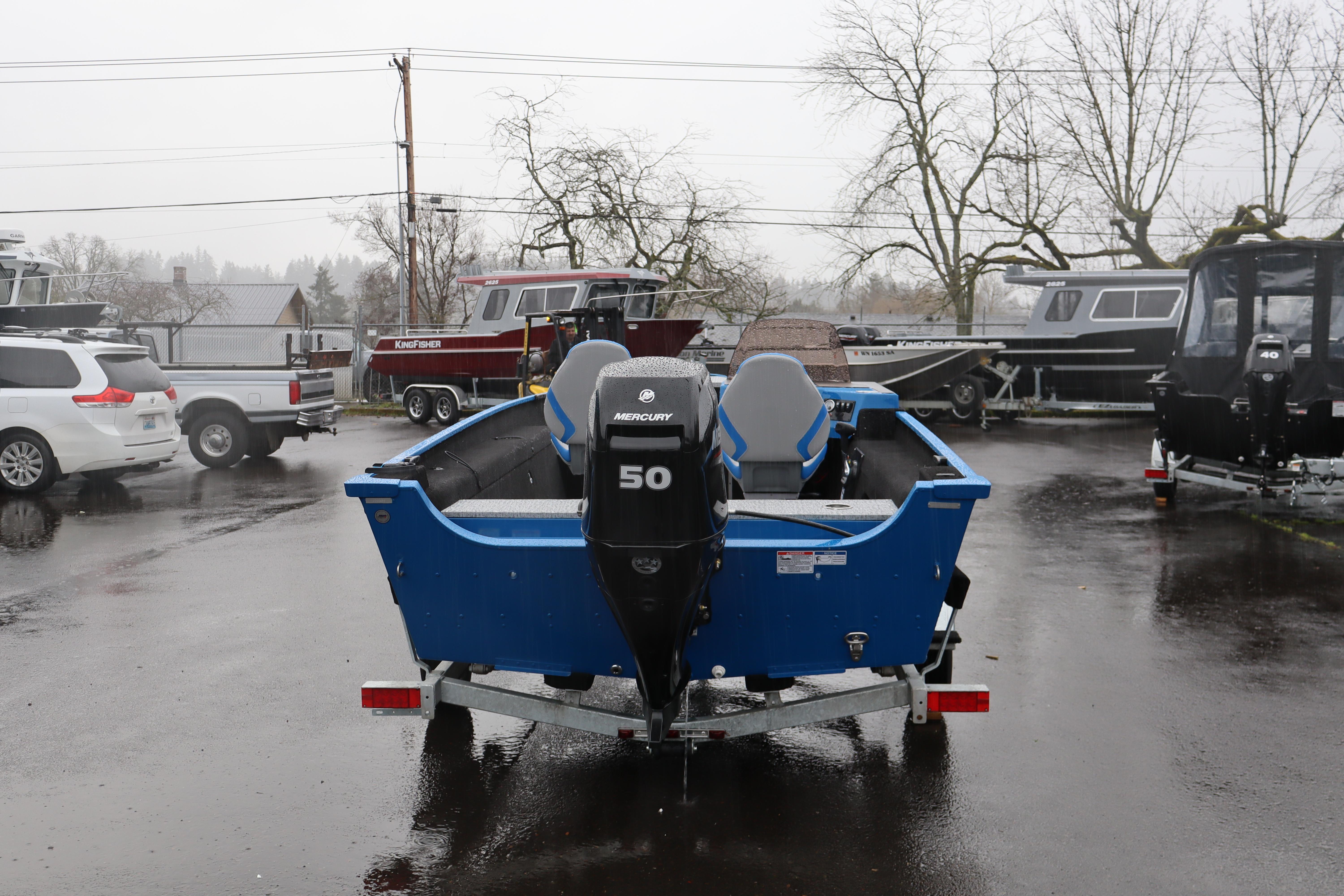 2026 Smoker Craft Lazer 161 boat with Mercury 50 engine in a rainy parking lot.