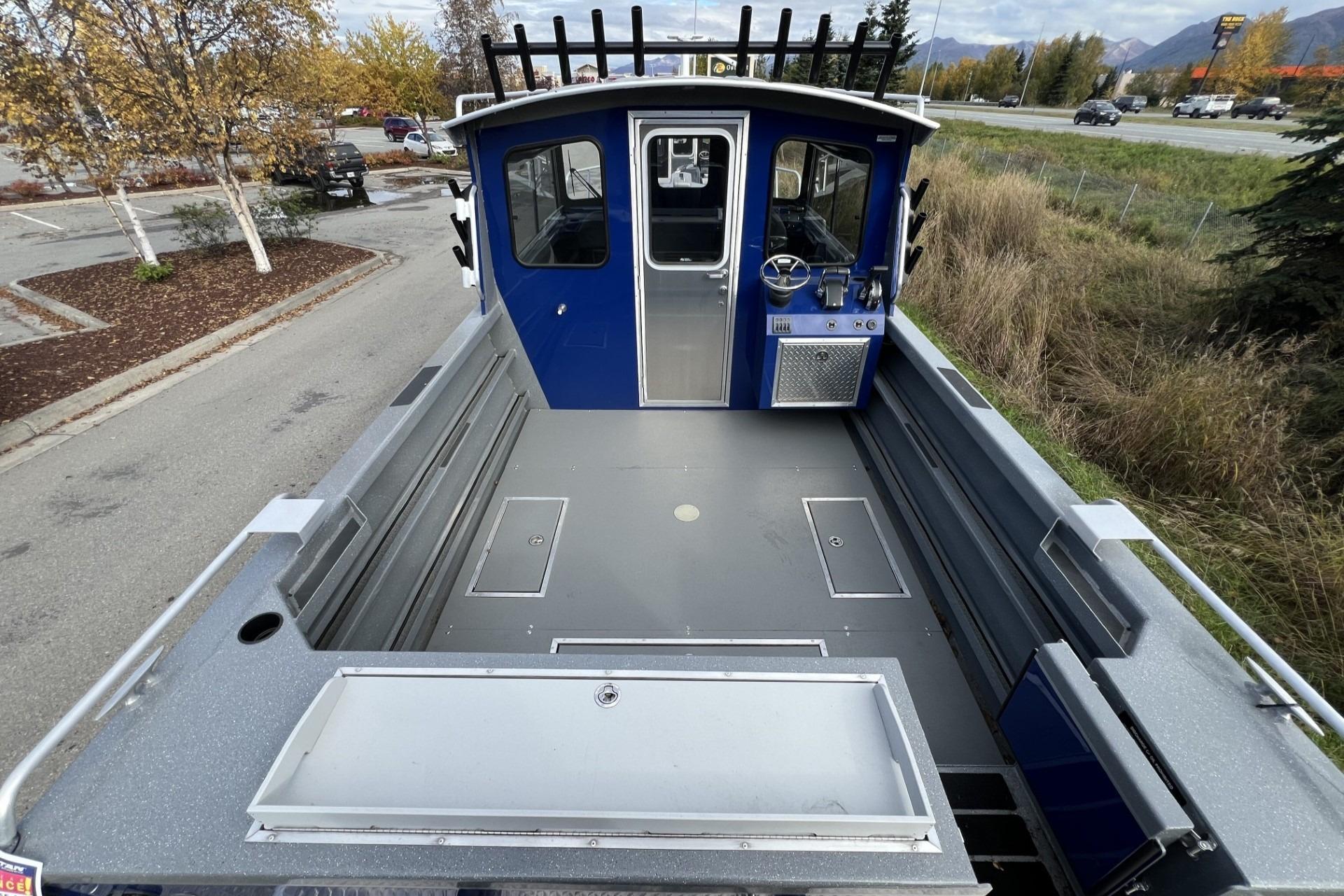 2024 Spartan 26 Maximus Pro XL boat, spacious deck, blue cabin, parked near road.