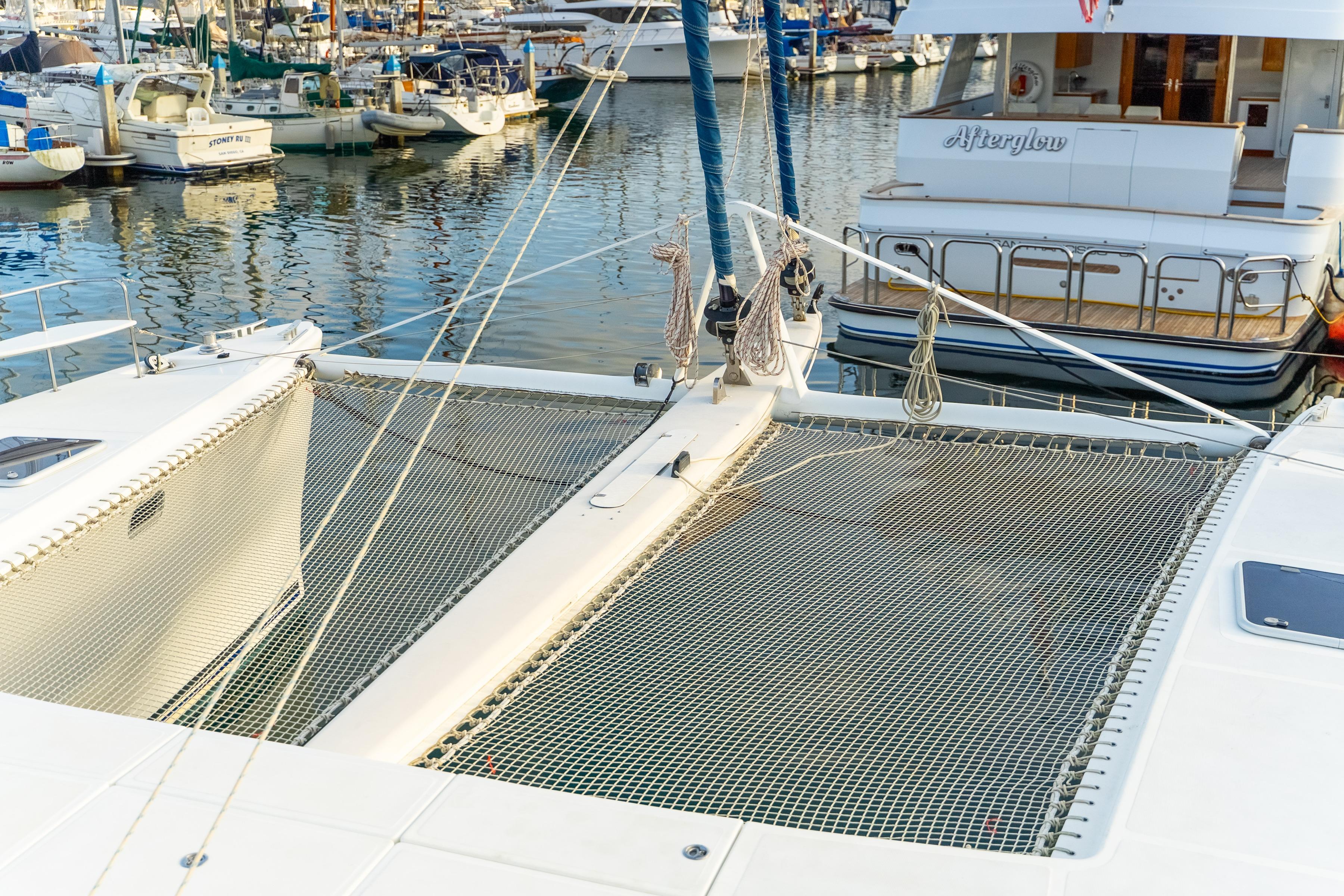 2009 Catana 65 catamaran docked in marina, showcasing netted deck and surrounding boats.