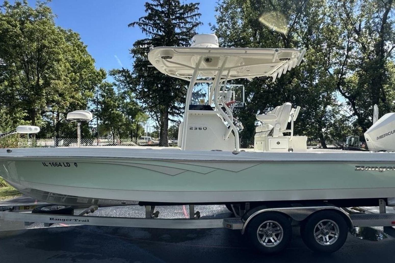 2022 Ranger 2360 Bay boat on trailer, parked outdoors with trees in background.
