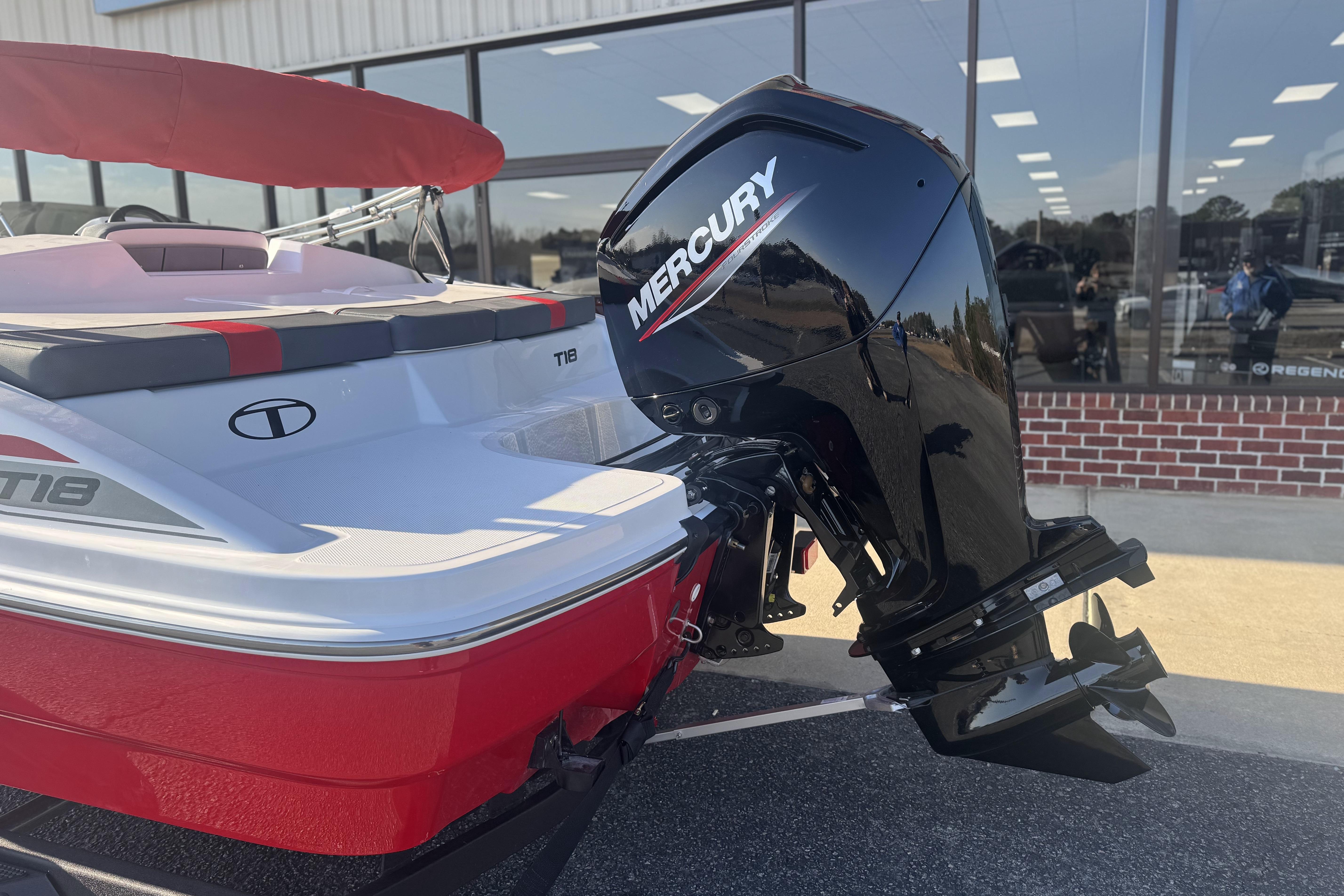 2026 Tahoe T18 boat with Mercury outboard motor, red and white design, parked outside showroom.