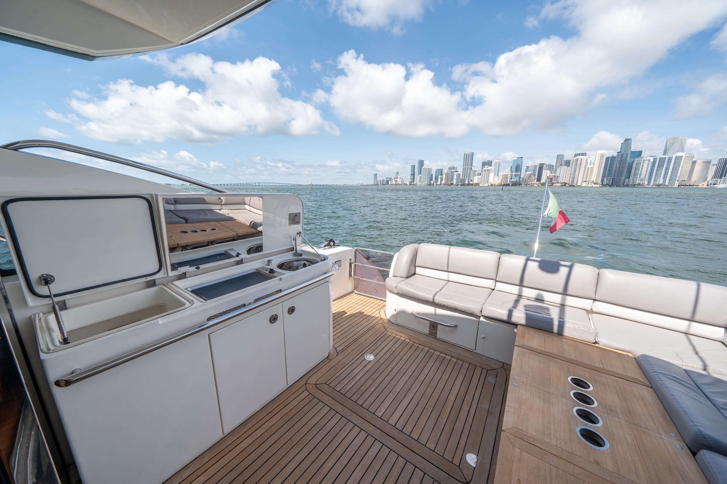 Luxurious 2012 Princess V52 yacht deck with city skyline view and outdoor kitchen.