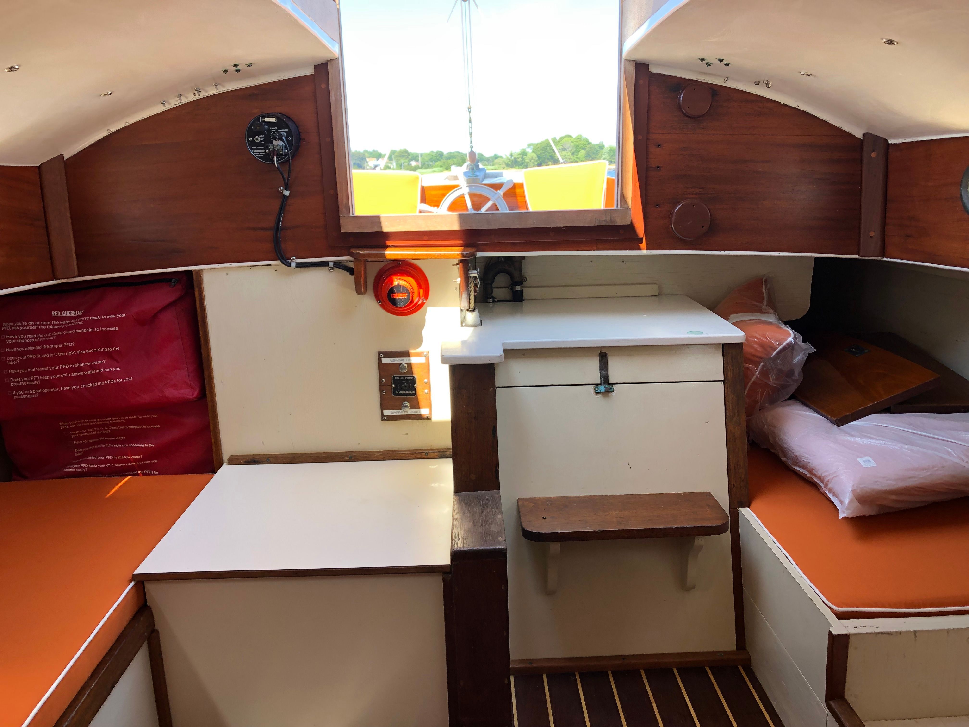 Interior of a 1973 Talman Yacht Menemsha-24 with wood accents and orange cushions.