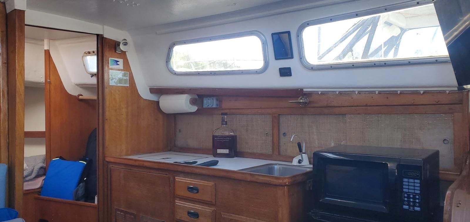 Interior of a Cal 29 yacht with wooden cabinetry, sink, and microwave.