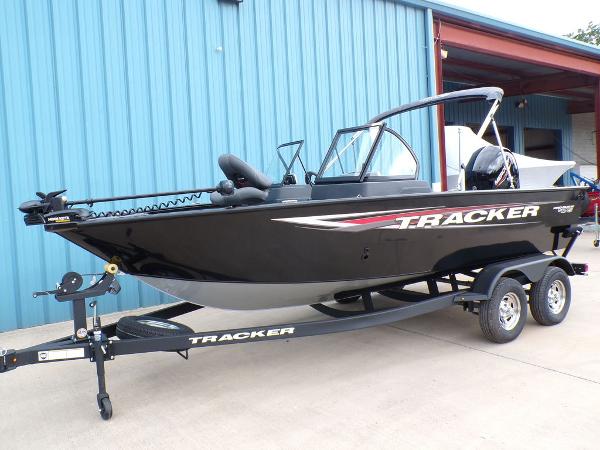 2025 Tracker Pro Guide V-175 Combo boat on trailer, parked by blue building.