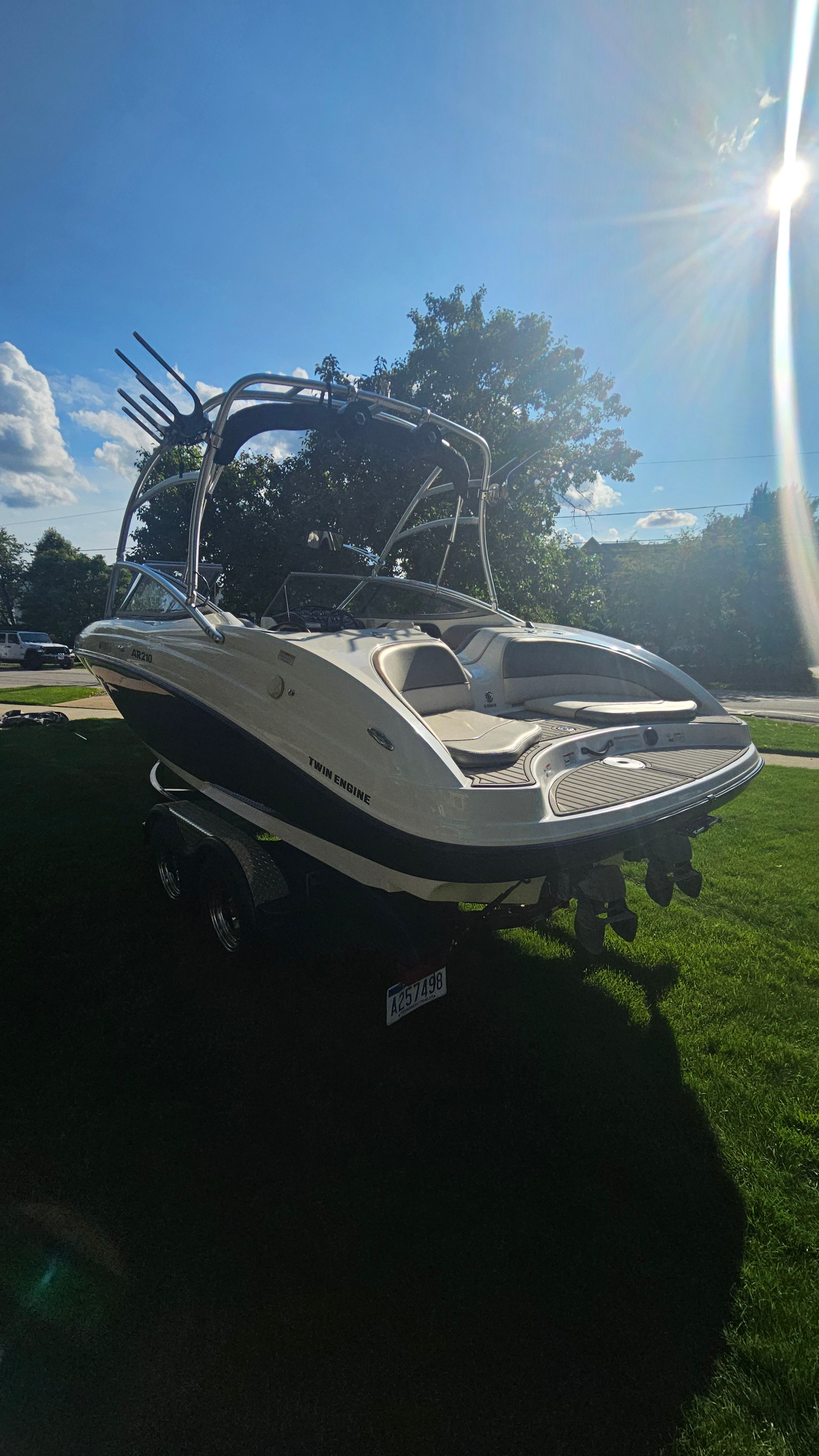 A 2010 Yamaha AR210 boat on a trailer, set on a green lawn.