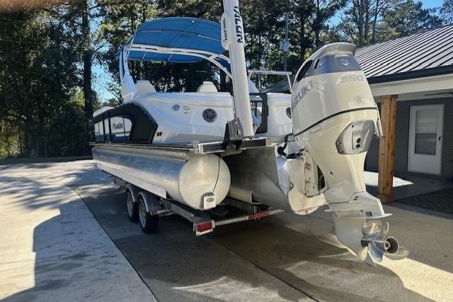 2020 Manitou 25 X-Plode RFW pontoon boat with Suzuki outboard motor on trailer.