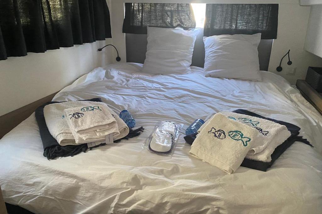 Cozy cabin bedroom in 2020 Fountaine Pajot Saona 47 catamaran with towels and bottled water.