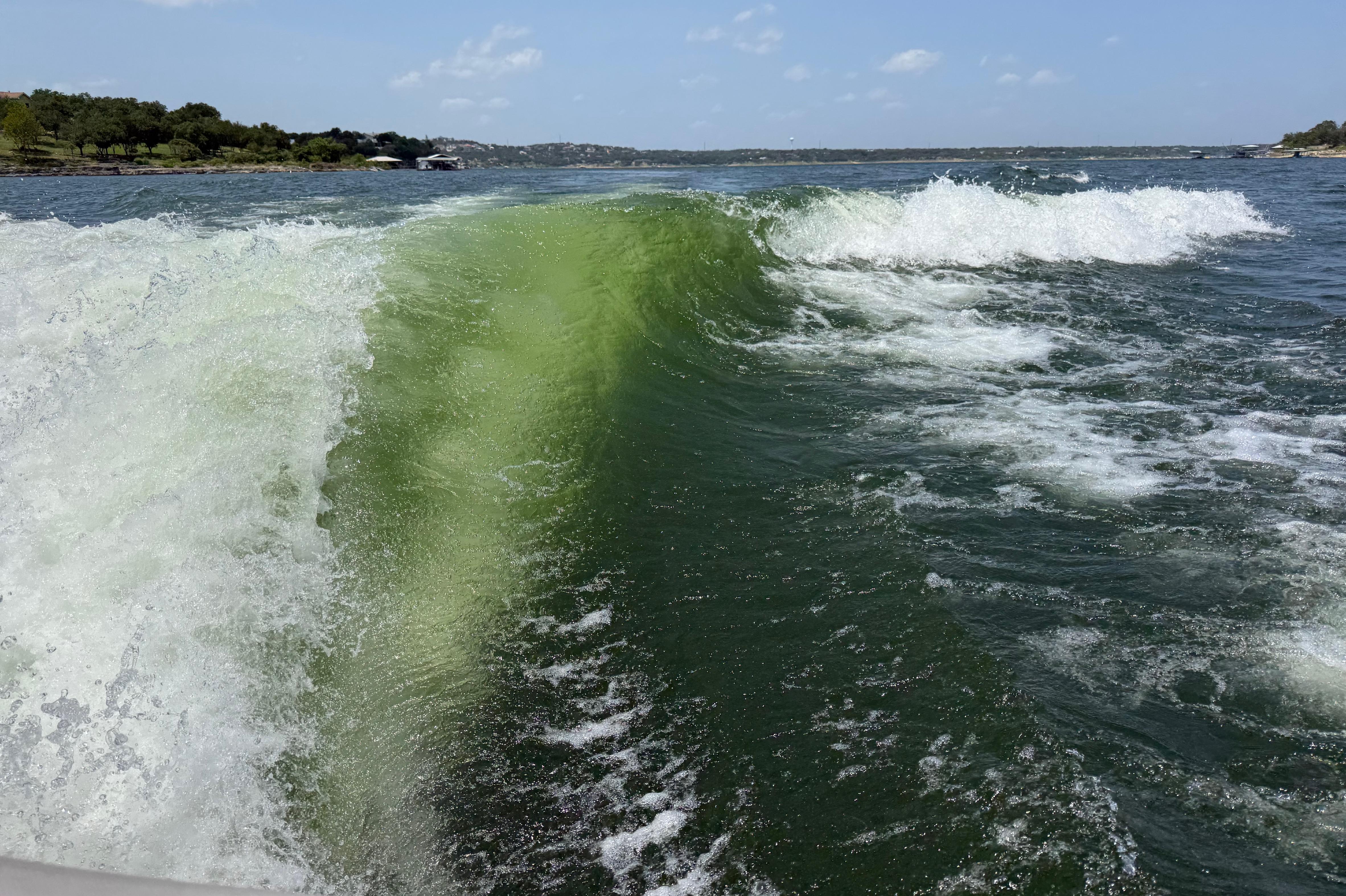 Wake surfing wave behind a 2017 Malibu M235 boat on a sunny lake.
