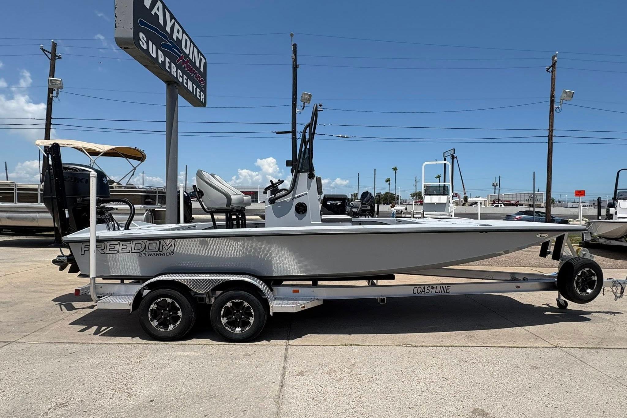 2026 Freedom Boats 23' Warrior on trailer at dealership under clear blue sky.