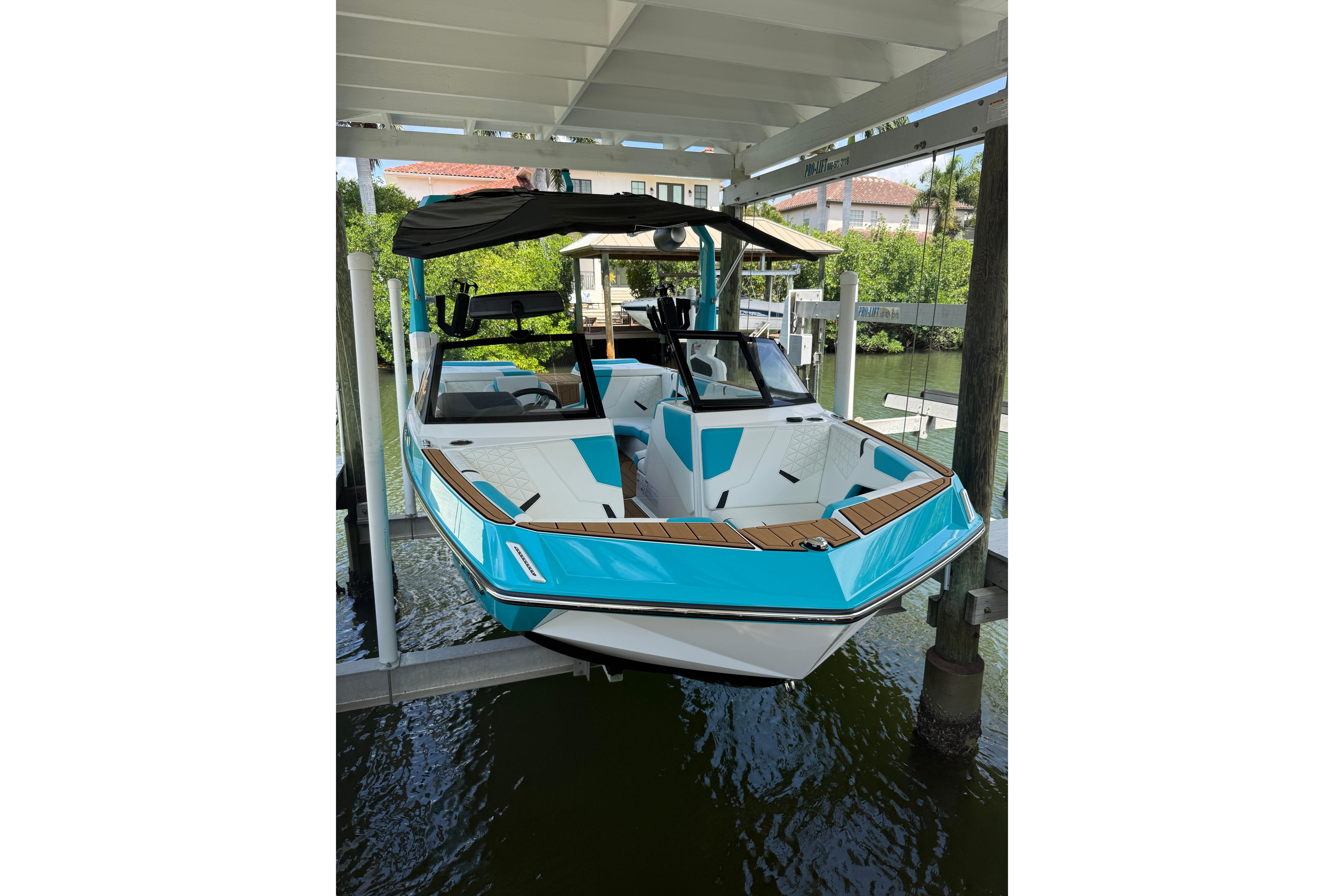 2024 Nautique Super Air Nautique GS20 in vibrant blue, docked under a covered lift.