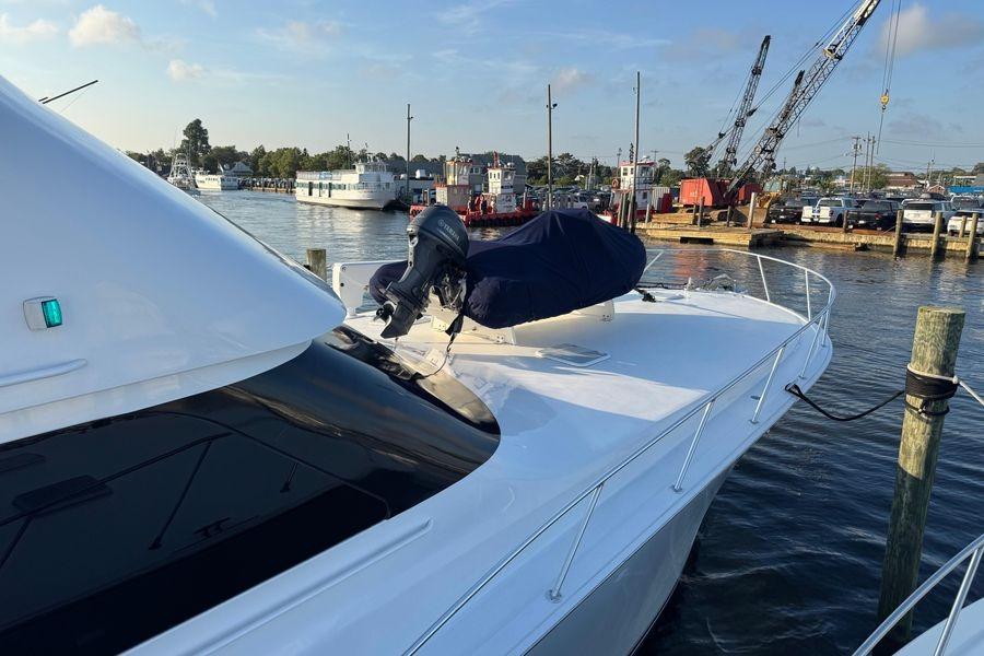 2002 Viking 61 Enclosed Bridge yacht docked at a marina, featuring sleek design.
