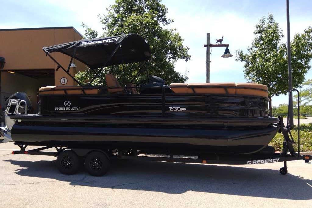 2026 Regency 230 DL pontoon boat on trailer, parked outdoors under clear sky.