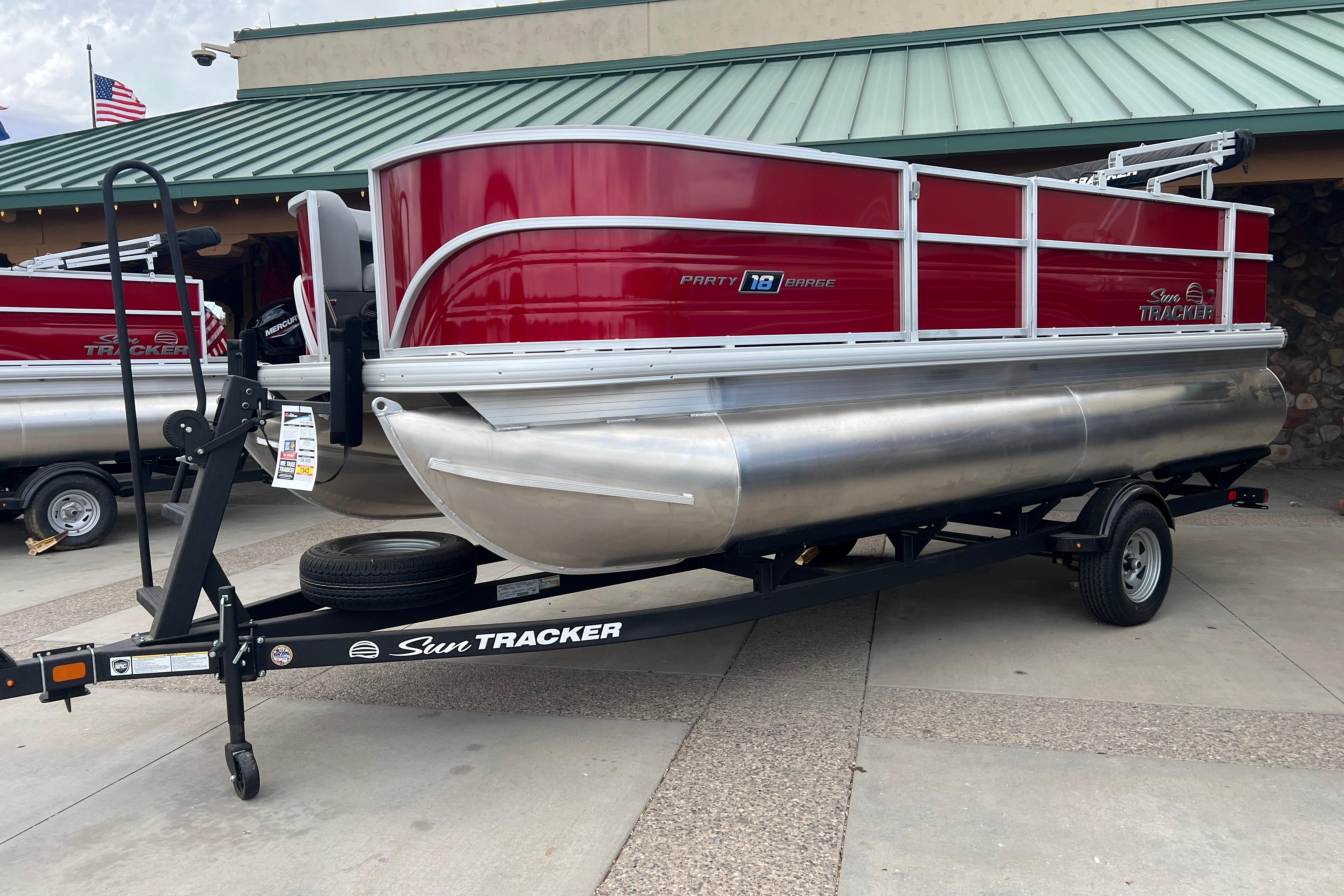 2026 Sun Tracker Party Barge 18 DLX pontoon boat on trailer, red and silver design.
