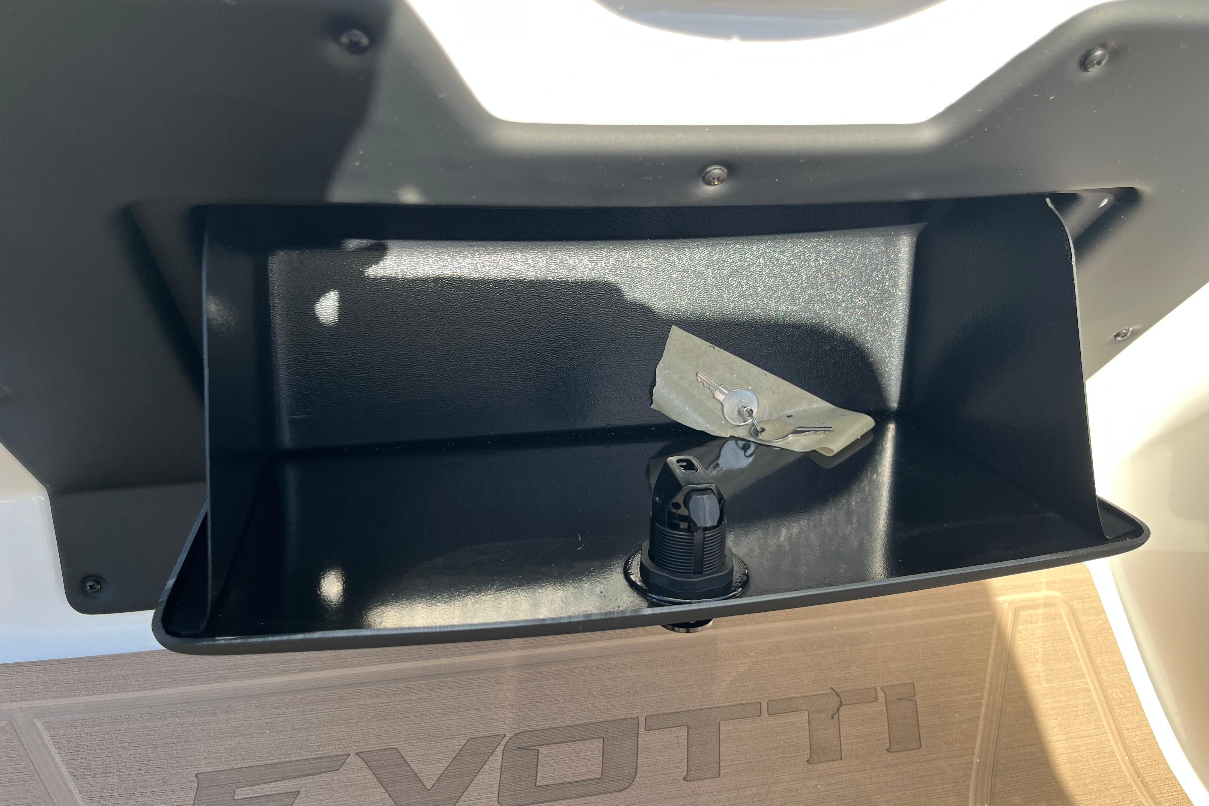 Open storage compartment in 2026 Evotti 523CS boat with key and plug.