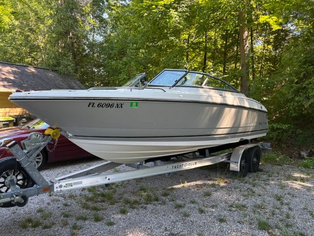 A white 2009 Monterey 234FS boat on a trailer in a wooded area.