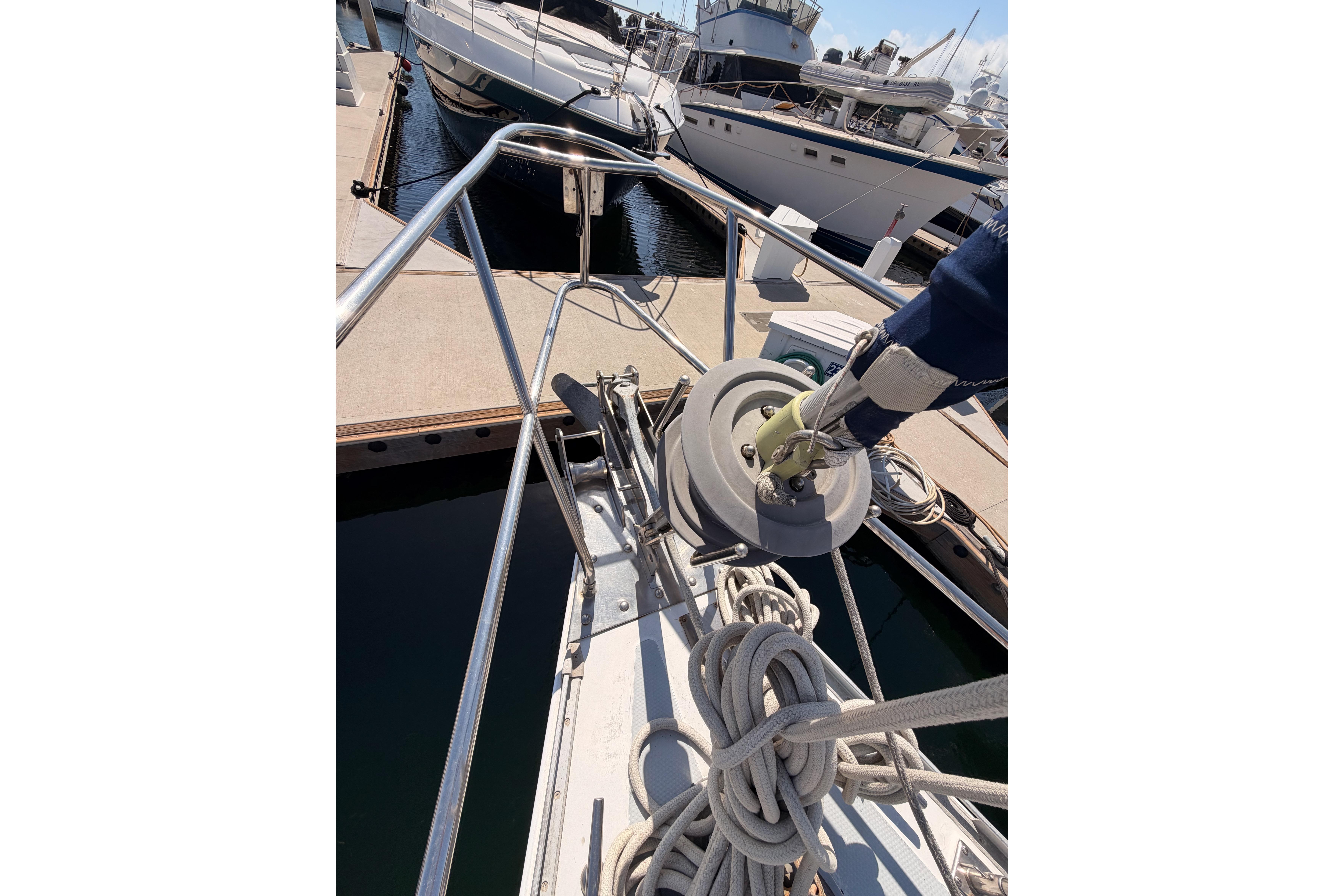 Bow of 1991 Hylas 51 yacht with ropes and docked boats in background.