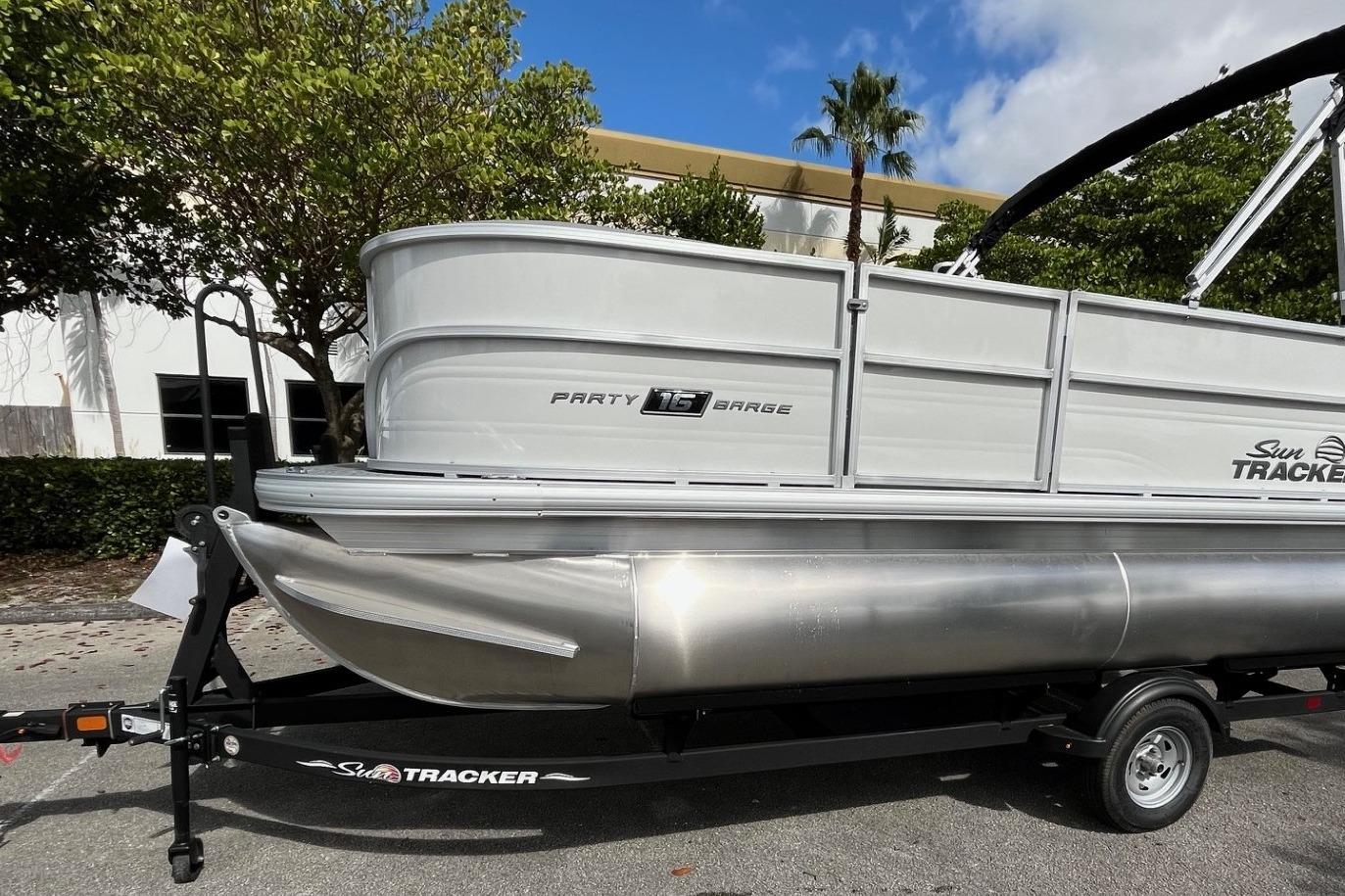 2026 Sun Tracker Party Barge 16 DLX pontoon boat on trailer, parked outdoors.