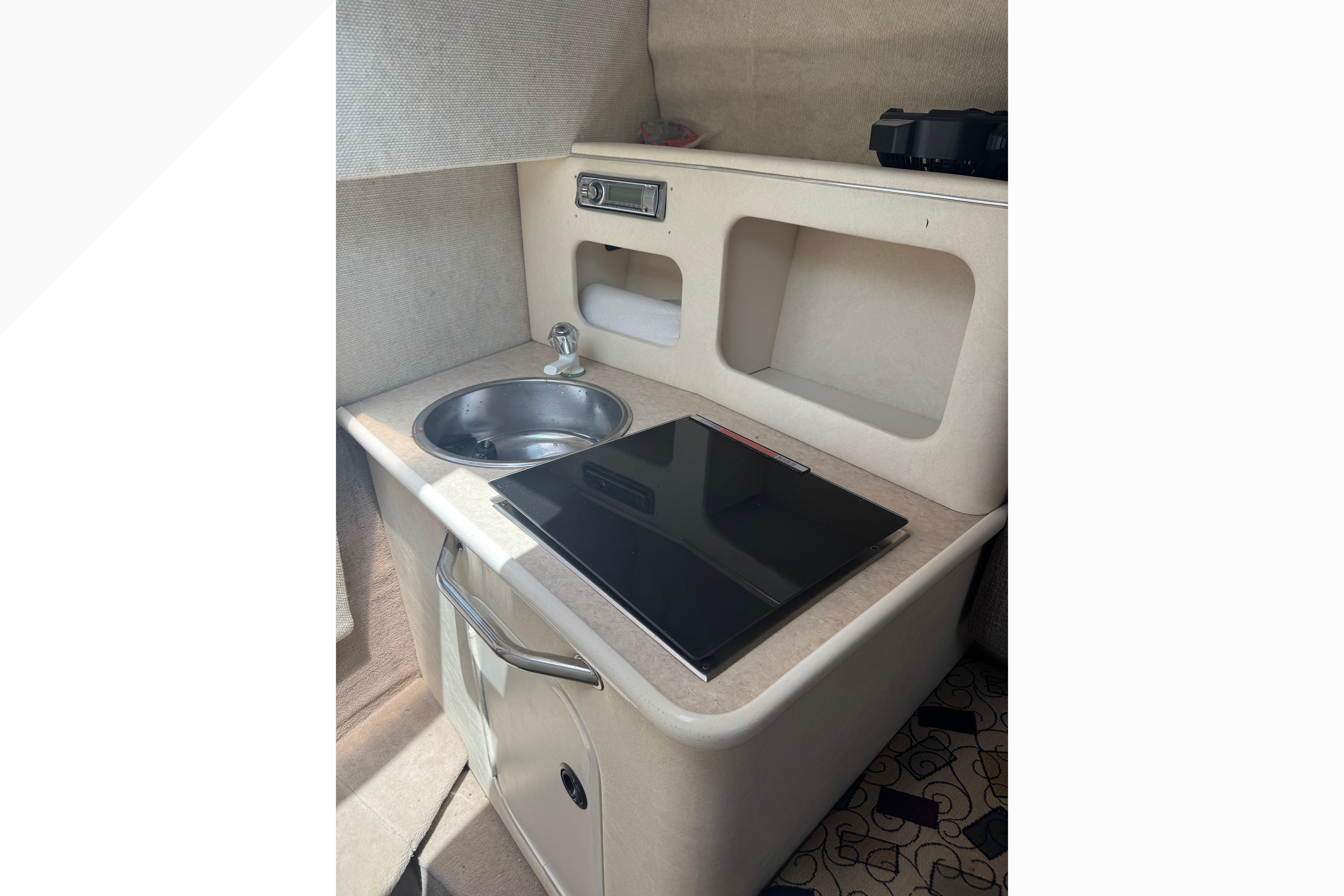 Compact kitchenette in a 2001 Sea Ray 245 Weekender boat, featuring a sink and storage.