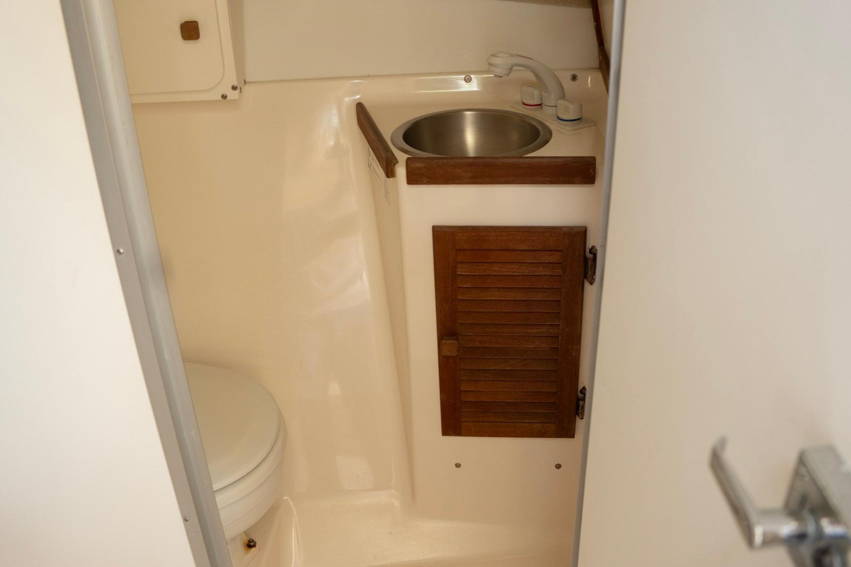 2006 Atlas Boat Works Acadia 25 interior bathroom with sink and wooden cabinet.