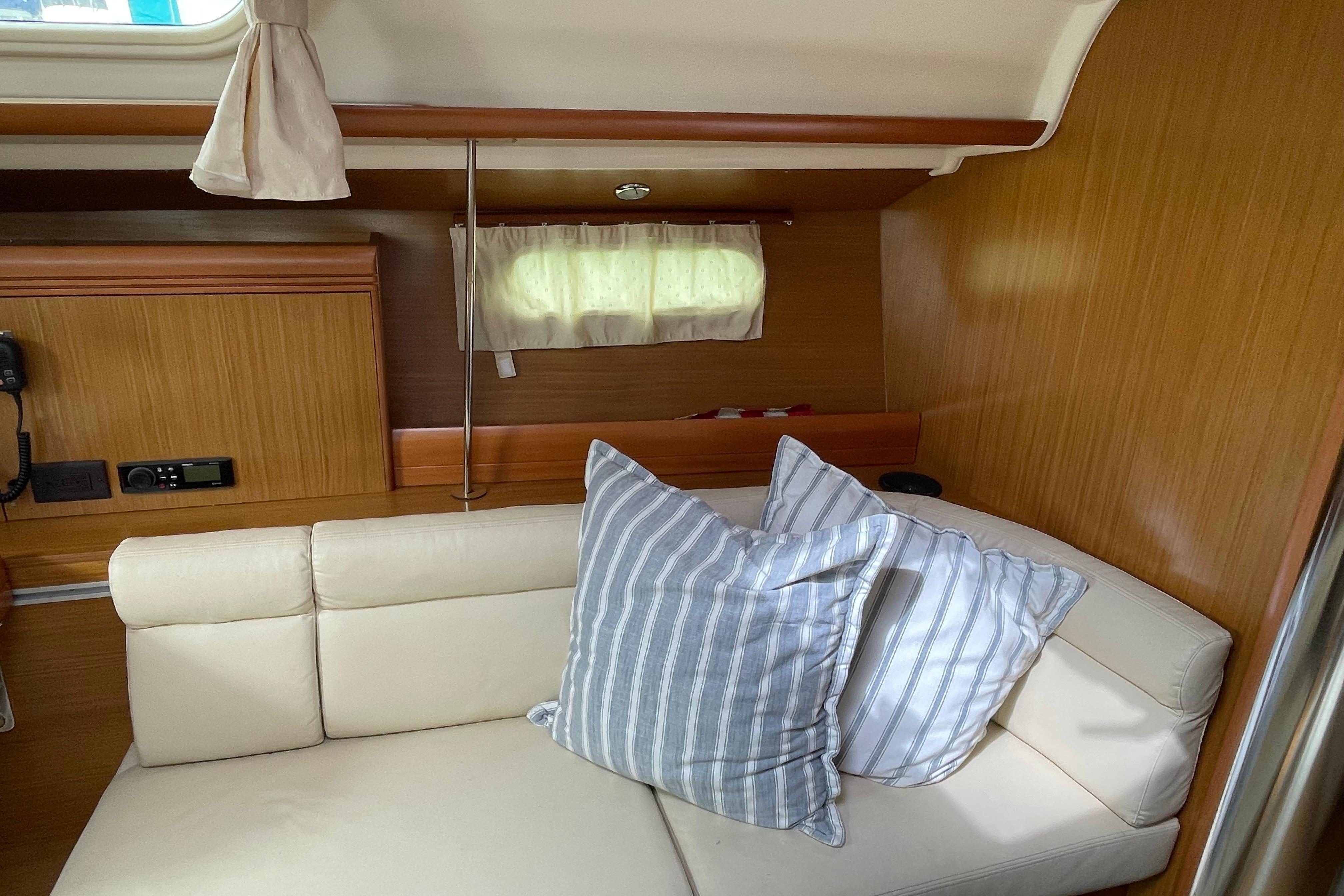 Interior of 2007 Jeanneau Sun Odyssey 39 DS with cozy seating and striped pillows.