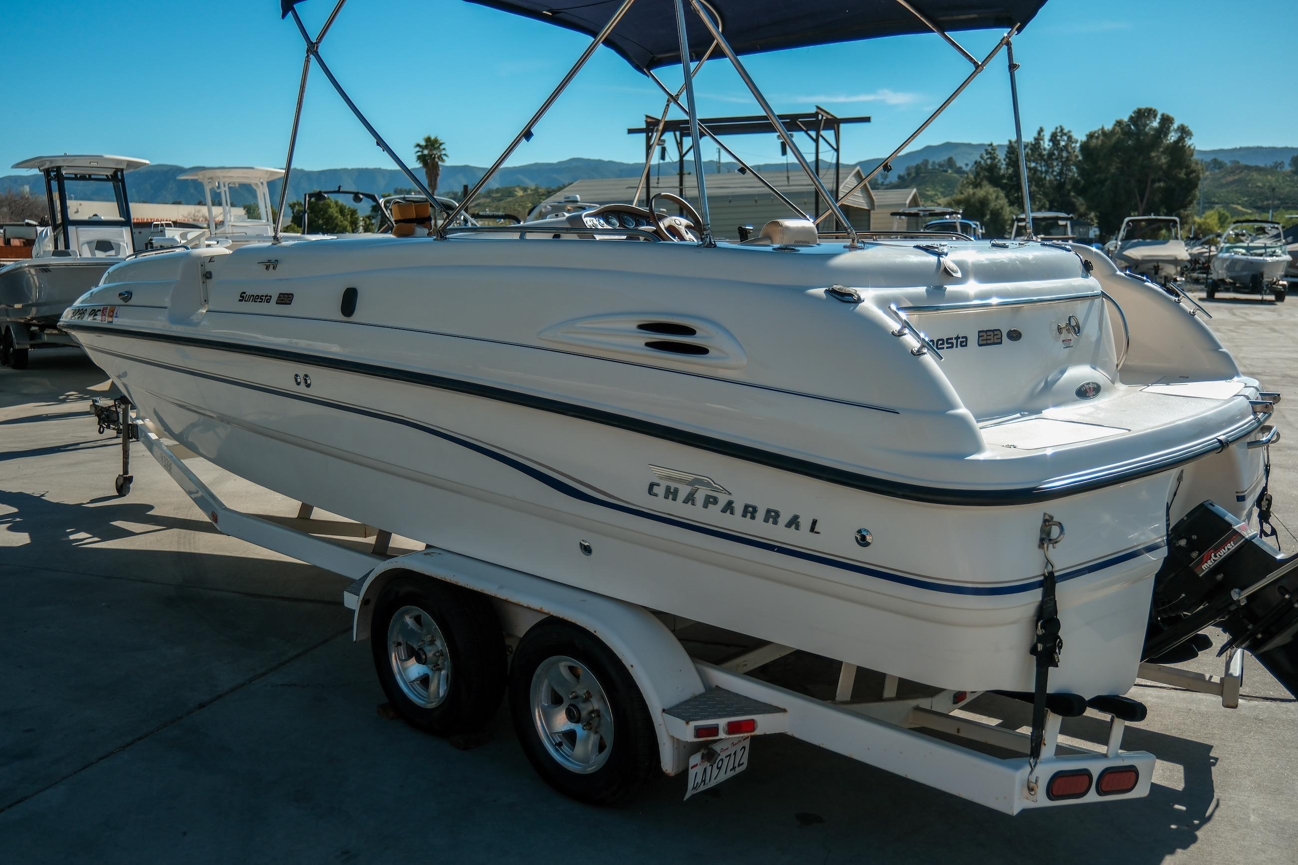 1998 Chaparral 232 Sunesta boat on trailer, parked outdoors under blue canopy.