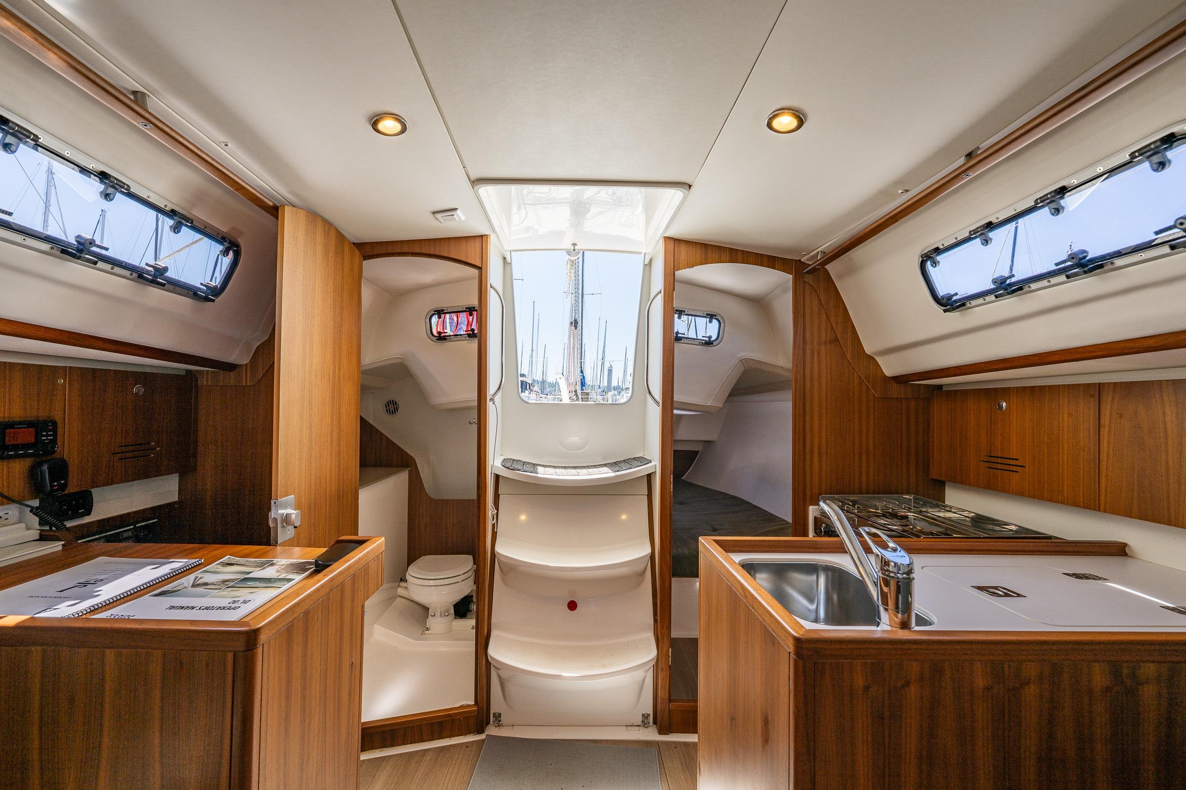 Interior of 2018 J Boats J/97E sailboat, featuring wood cabinetry, kitchenette, and compact bathroom.