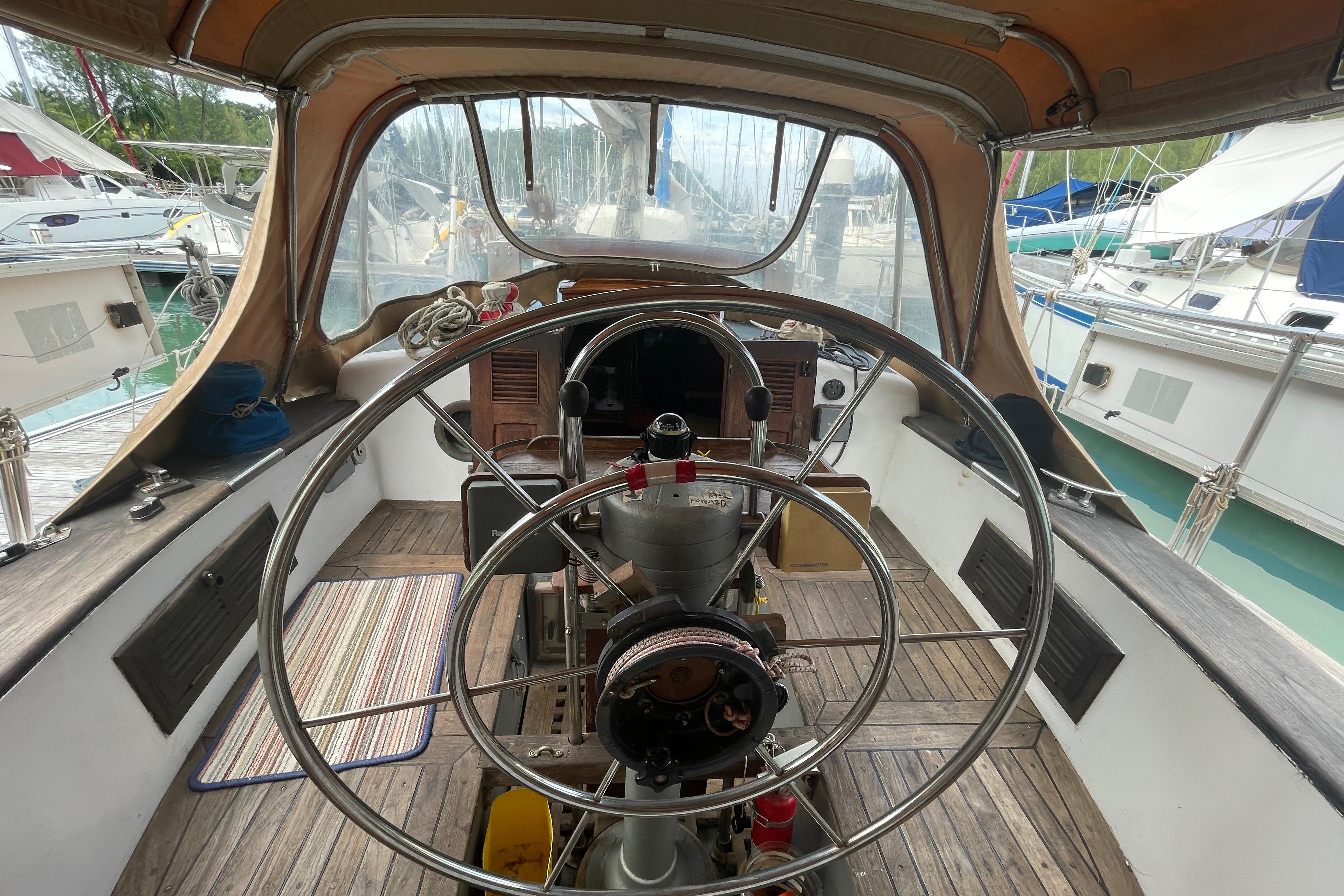 1979 Westwind 35 sailboat cockpit with steering wheel and marina view.