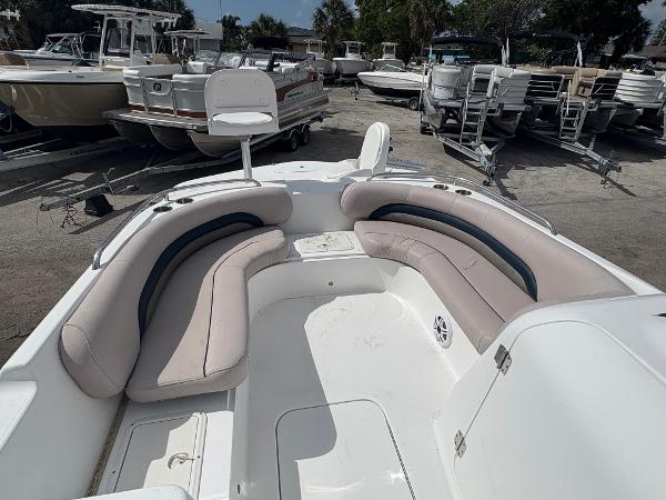 2014 Hurricane SunDeck Sport 232 OB boat with spacious seating, docked among other boats.