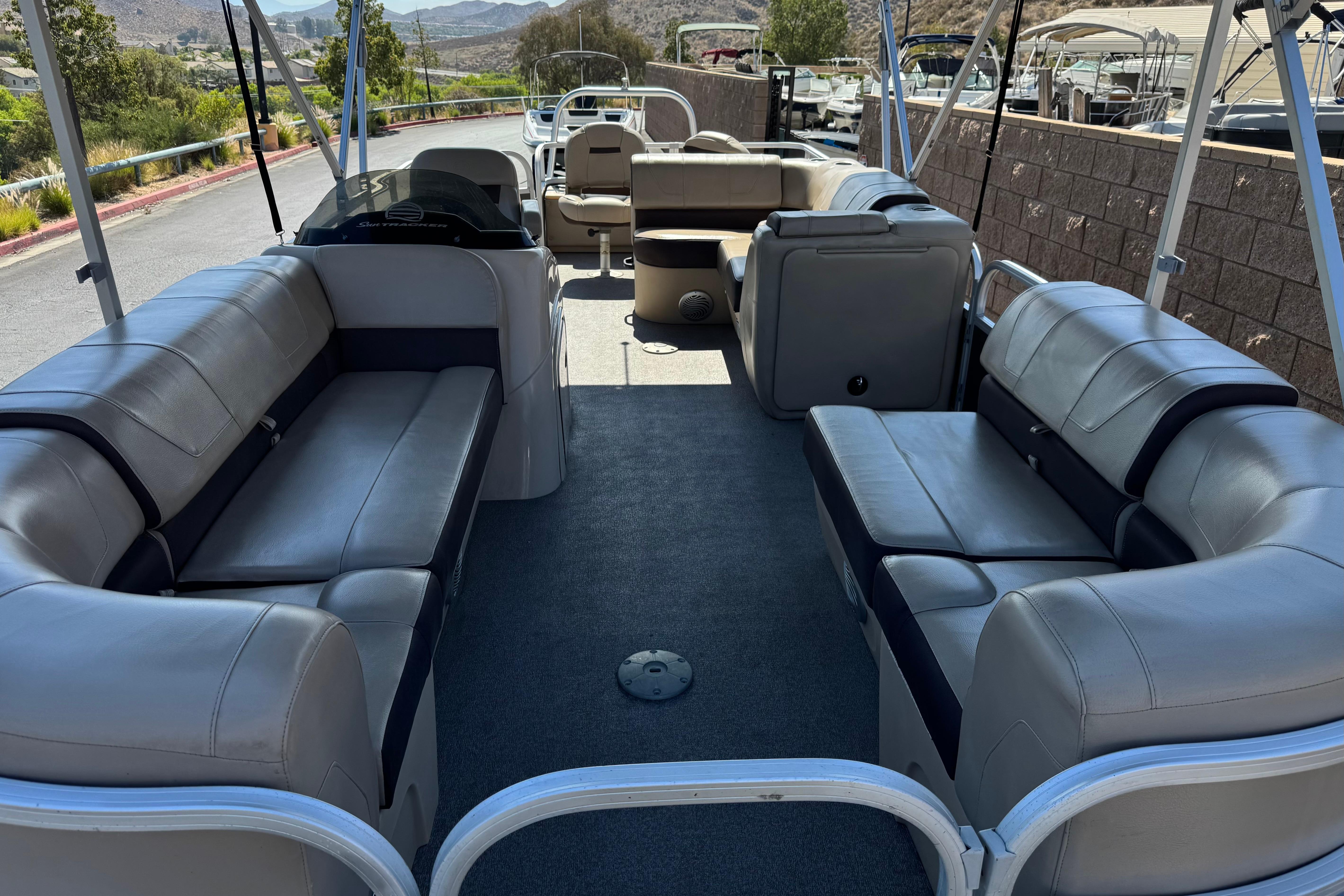 2018 Sun Tracker SportFish 22 DLX pontoon boat with spacious seating and scenic background.