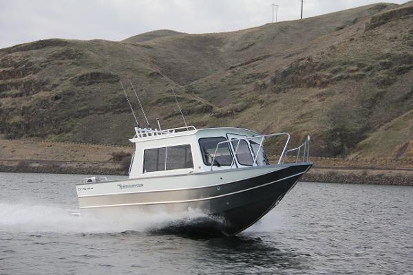 2023 Spartan 220 Maximus Pro boat cruising on a lake with hills in the background.
