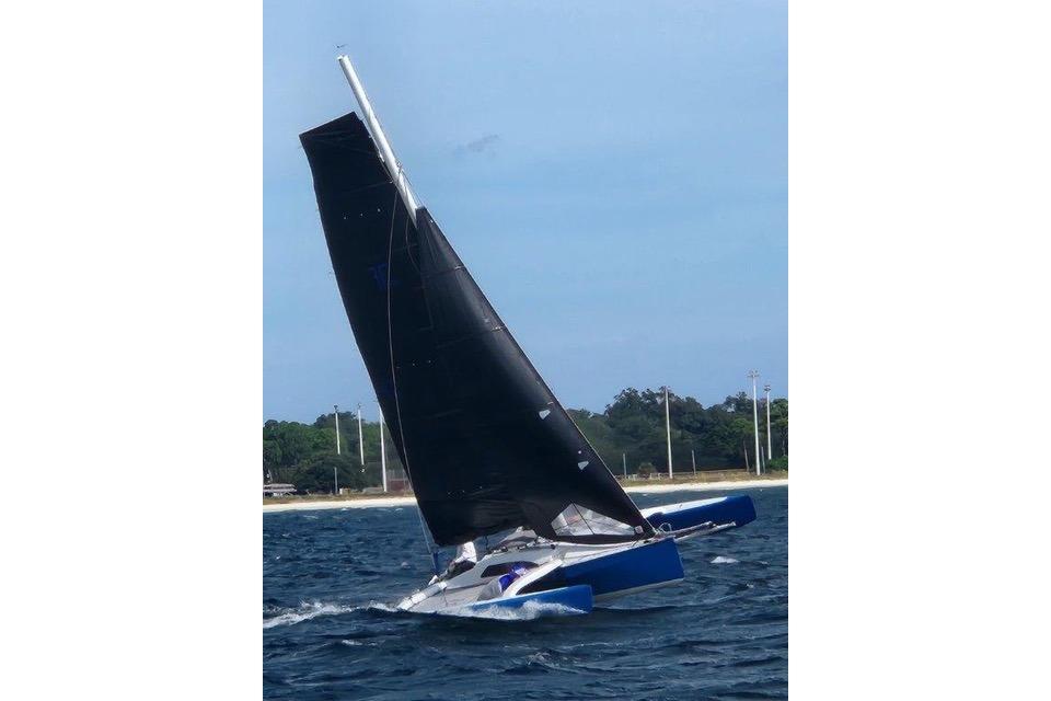 Sailing Farrier F-25C trimaran on open water, 1996 model, with black sails.