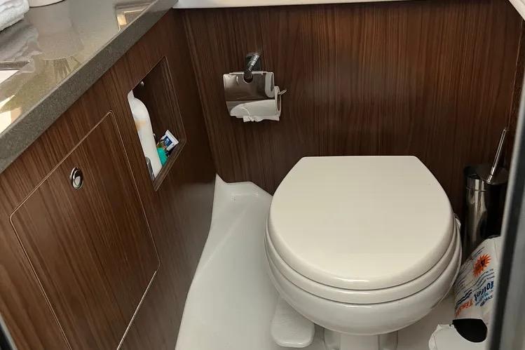 2023 Four Winns H350 OB boat bathroom with wood paneling and modern fixtures.