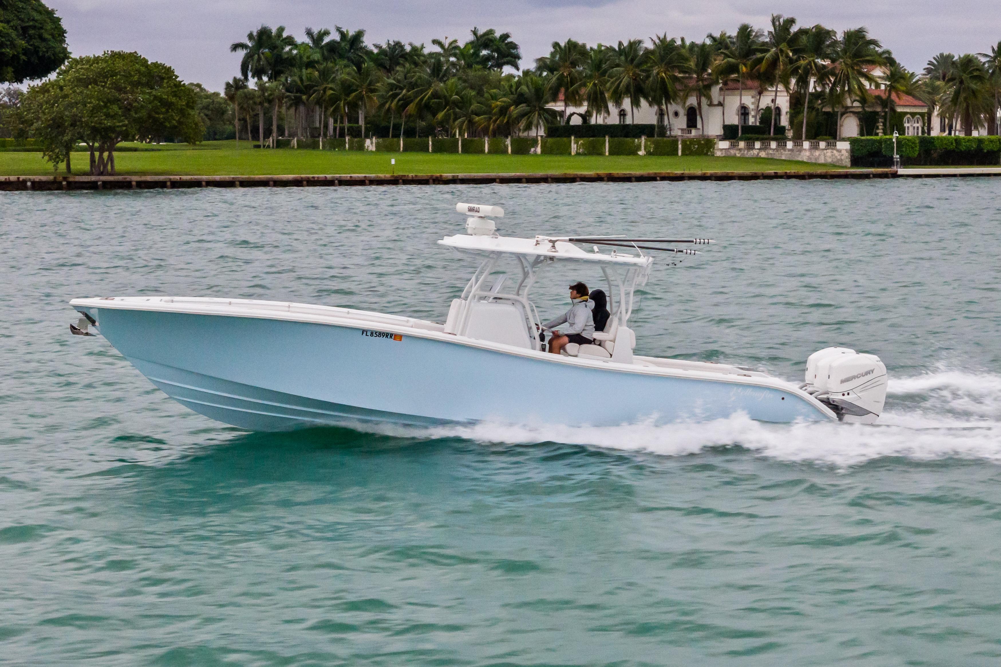 2021 Yellowfin 36 Offshore boat cruising on water near palm trees.
