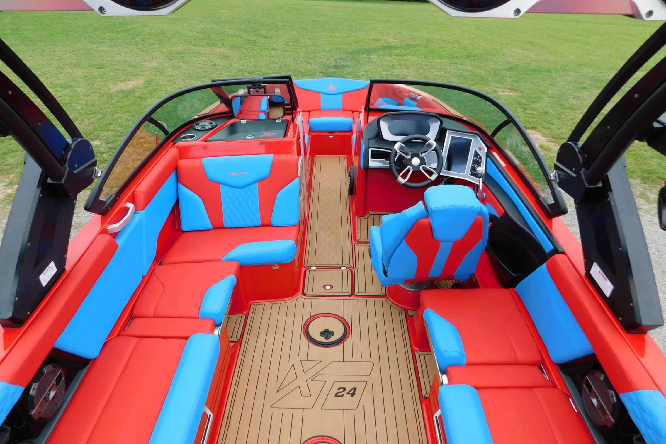 2022 MasterCraft NXT24 boat interior with vibrant red and blue seating, modern dashboard, and wood-style flooring.