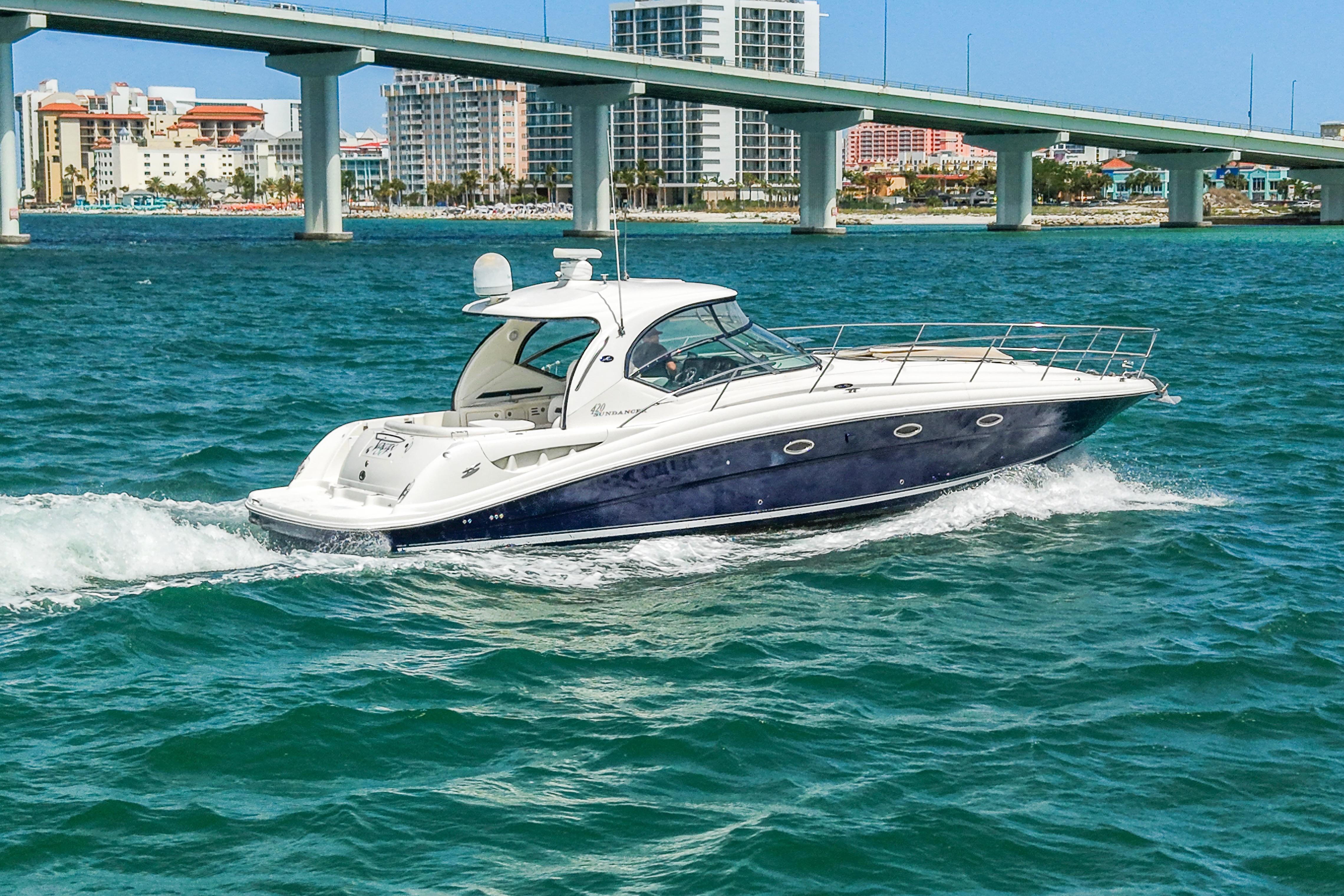 2004 Sea Ray 420 Sundancer cruising under a bridge in clear blue waters.