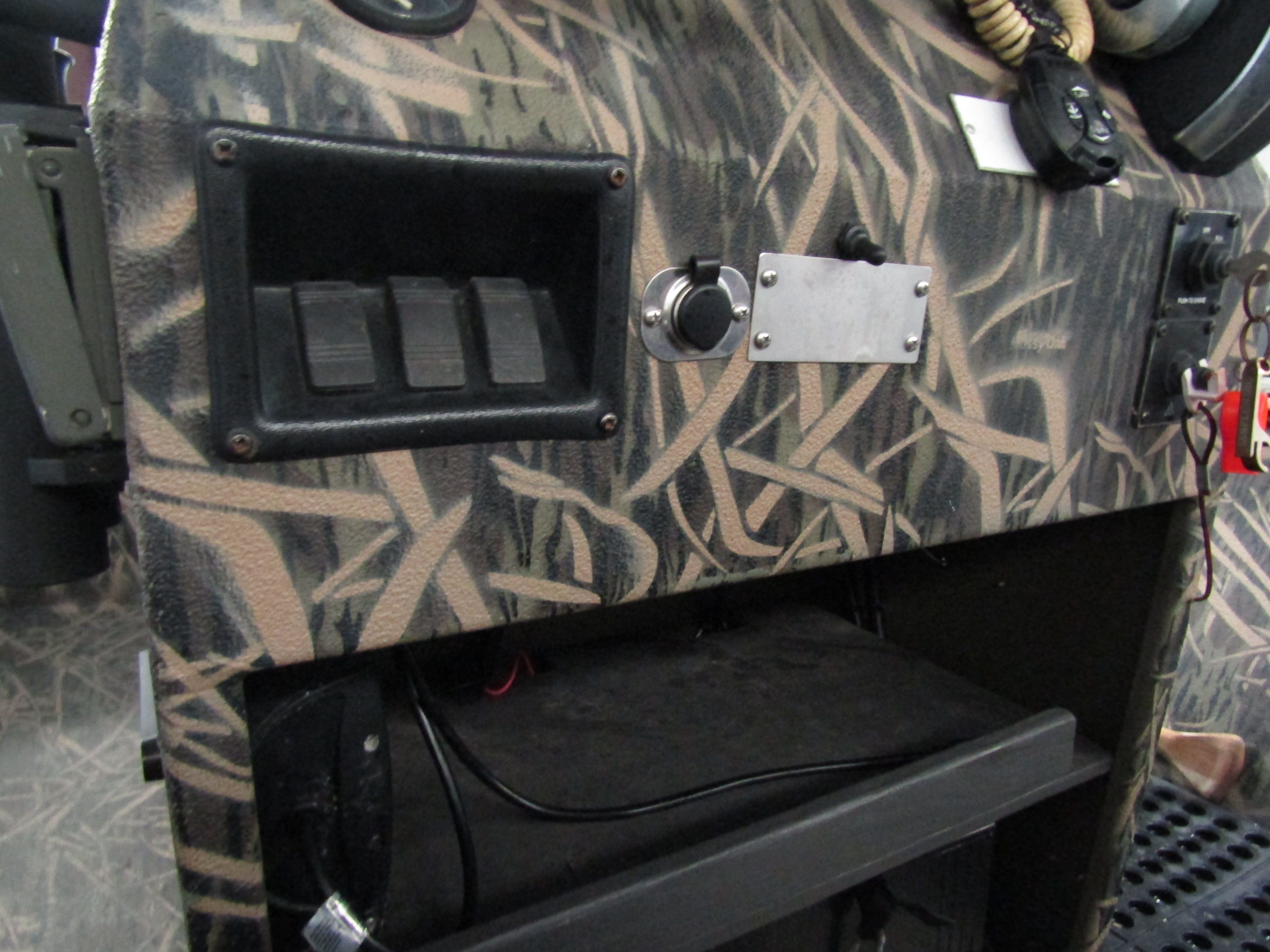 Close-up of a boat dashboard with camouflage pattern and switches.