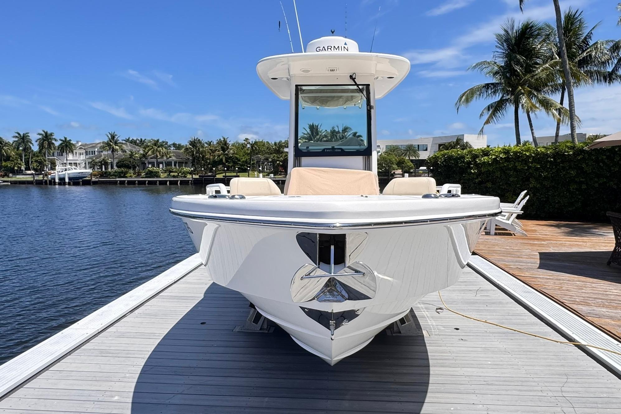 2018 Everglades 253 Center Console boat docked by a scenic waterfront with palm trees.
