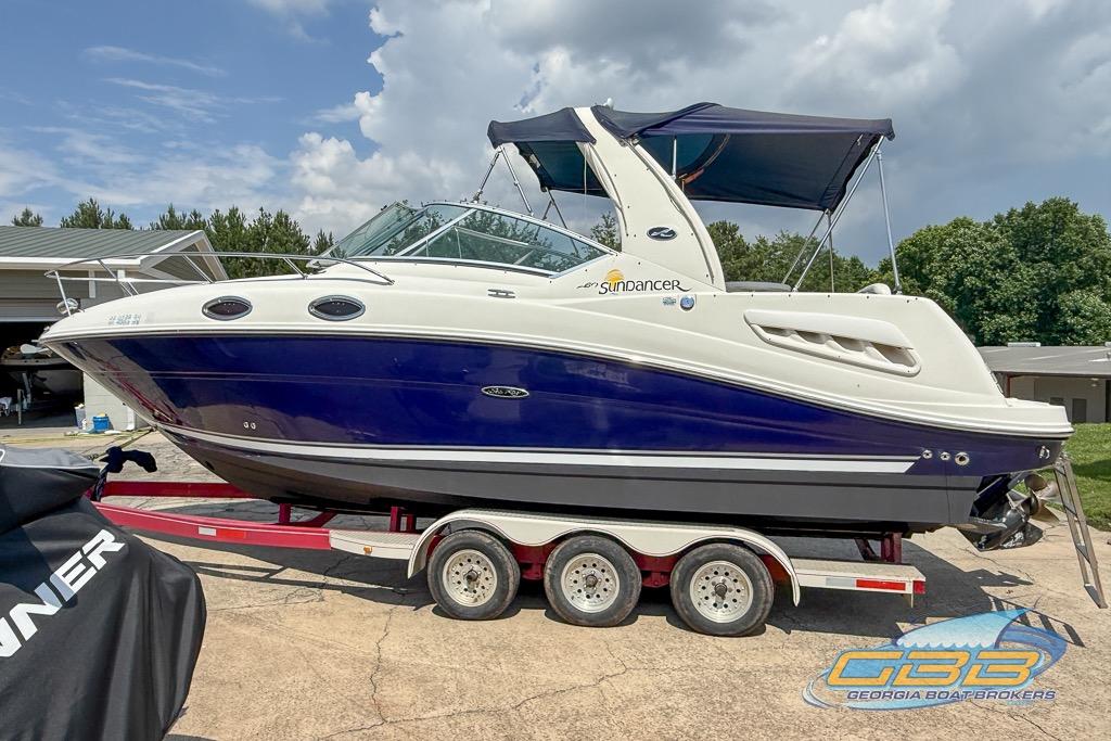 2006 Sea Ray Sundancer 260 boat on trailer, blue and white design, parked outdoors.