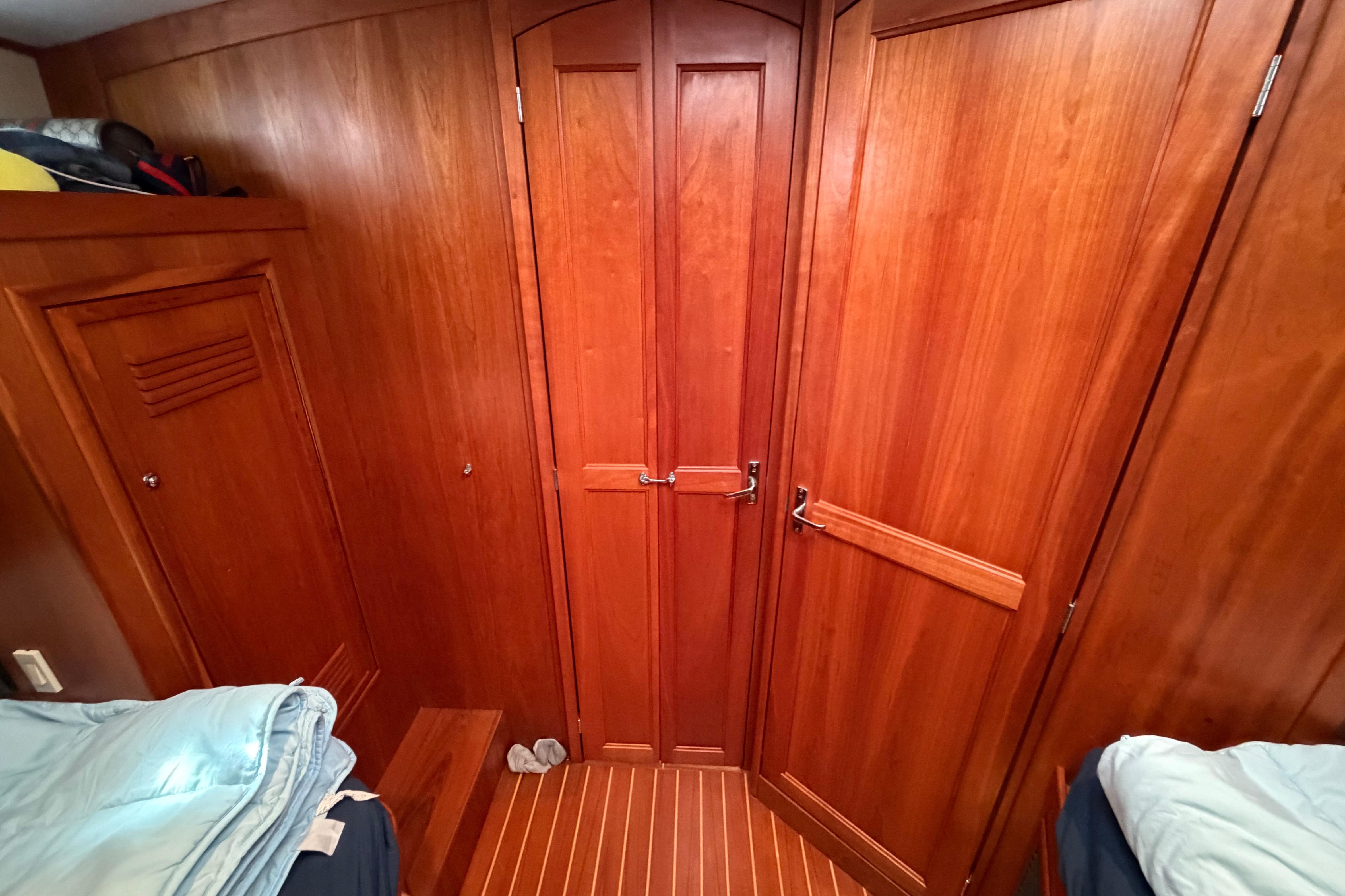 Wood-paneled cabin interior of 2000 Sabreline 36 Express yacht, featuring cozy bedding and storage.