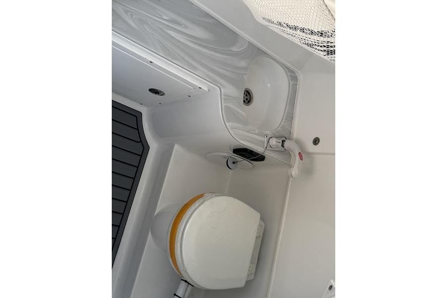 Interior of 2026 Sea Hunt Gamefish 30, featuring a compact marine toilet and sink.