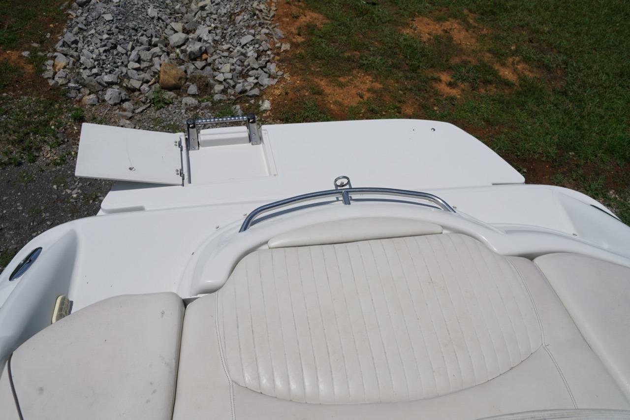 2004 Crownline 216 LS boat with white seating and swim platform, on grassy terrain.