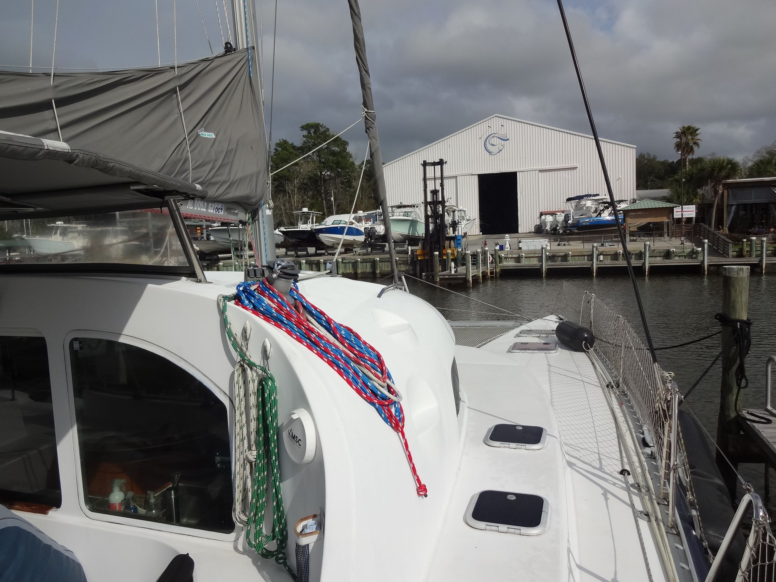2003 Lagoon 410 catamaran docked with shipyard in background.