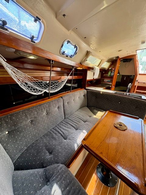 Interior of a 1989 Catalina 34 with a cozy seating area and wooden table.