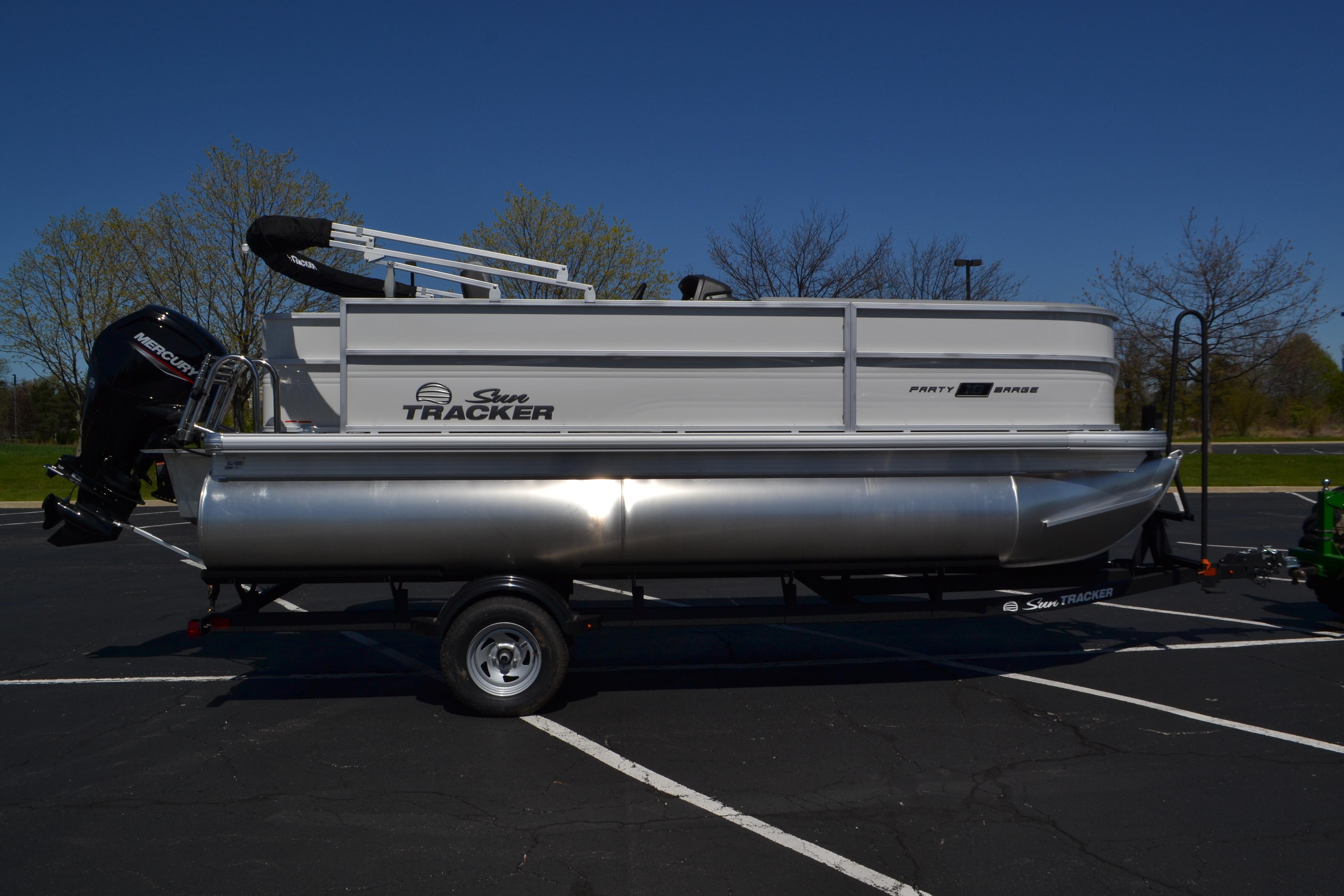 2026 Sun Tracker Party Barge 18 DLX pontoon boat on trailer in parking lot.