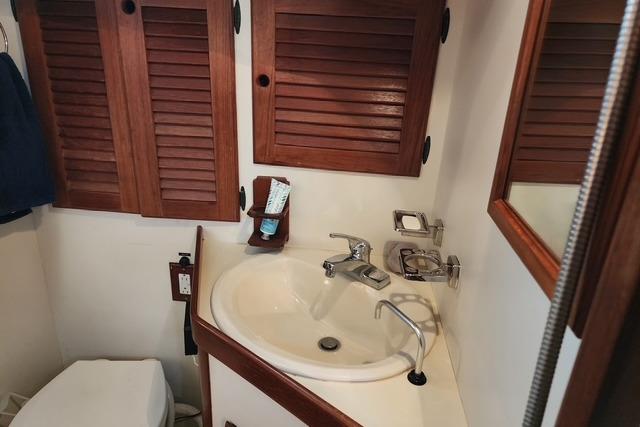 1984 Bristol 45.5 Center Cockpit bathroom with wooden cabinets and sink.